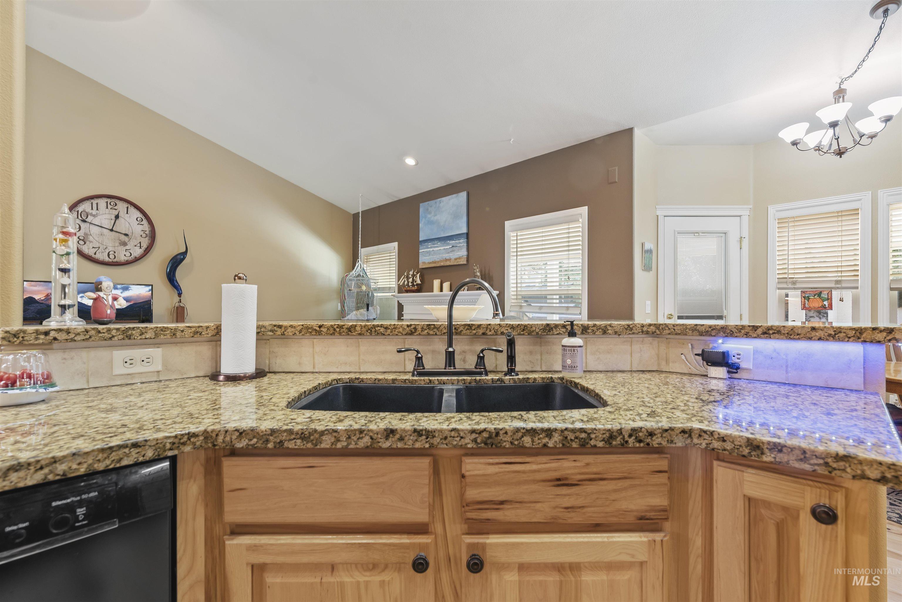 Kitchen with black dishwasher, light stone countertops, decorative light fixtures, light brown cabinetry, and recessed lighting