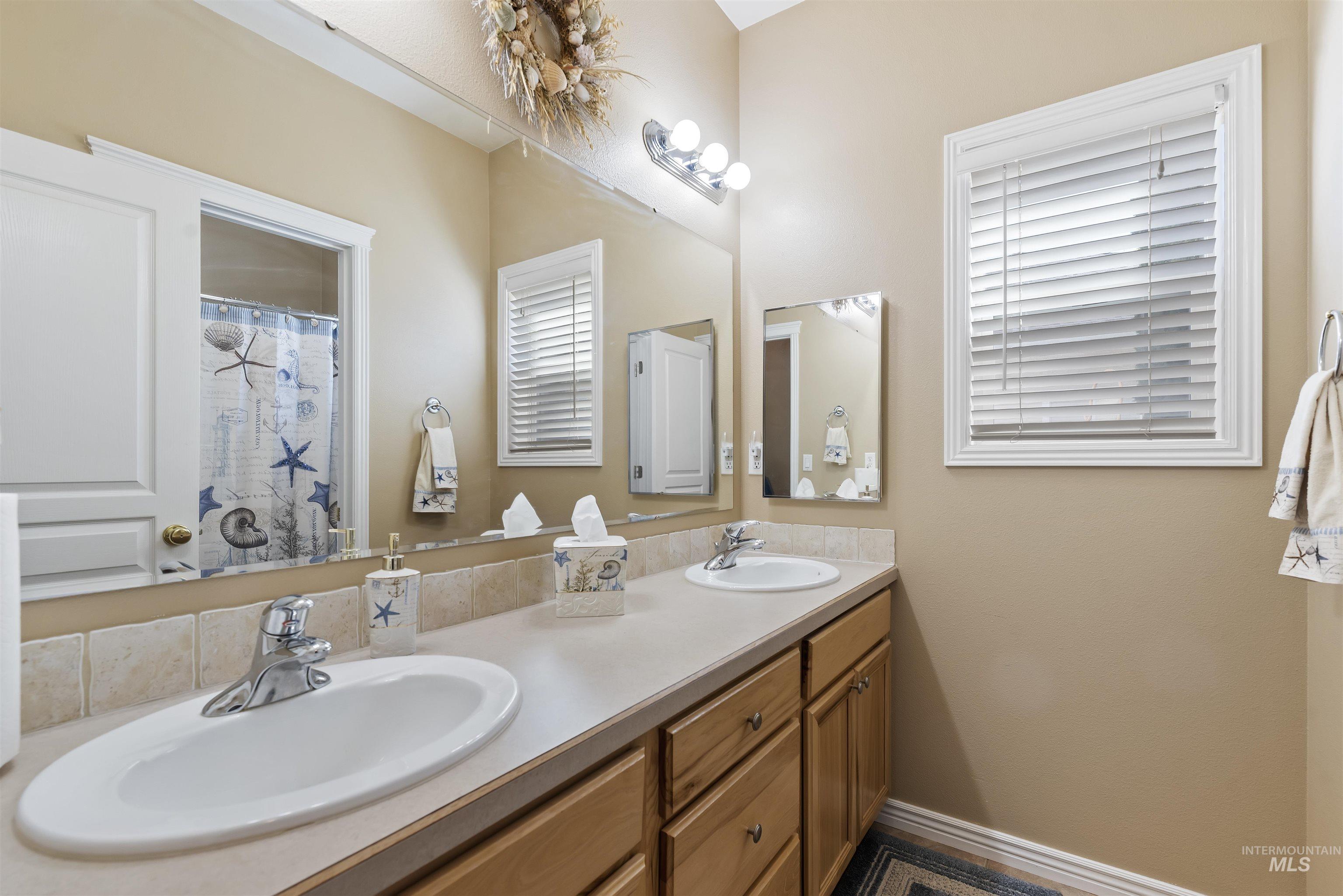 Bathroom with double vanity and baseboards