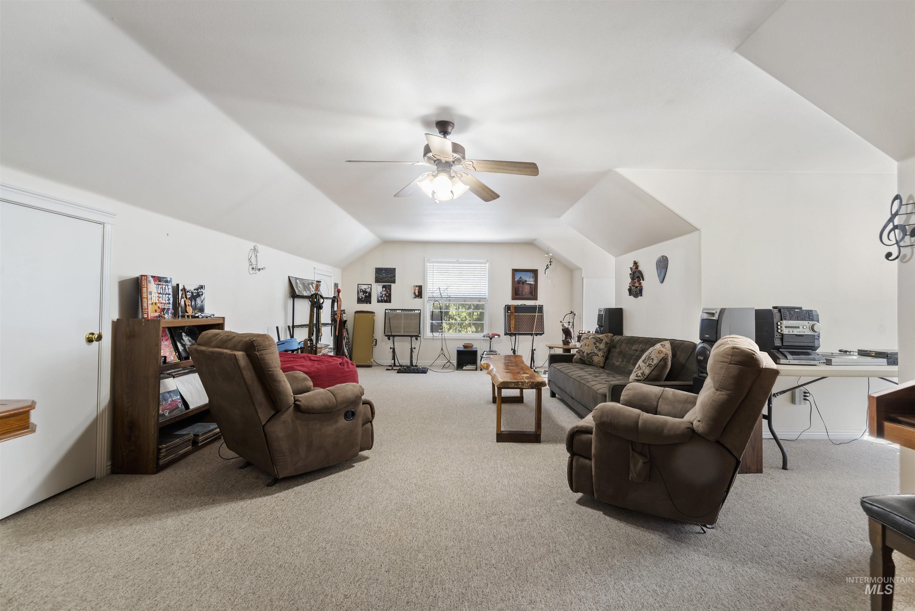 Carpeted living room with lofted ceiling, a desk, and ceiling fan