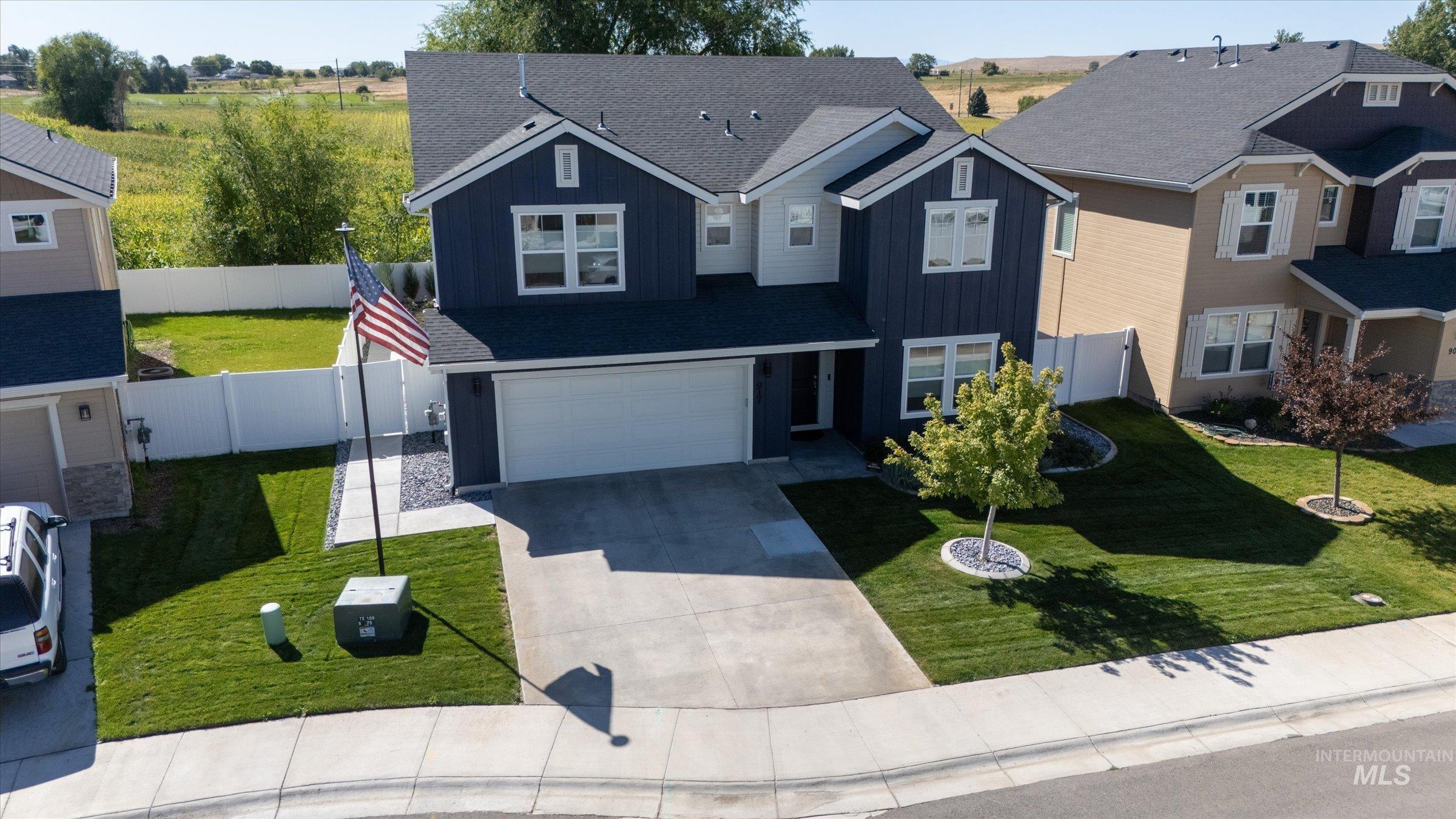 Traditional-style home with board and batten siding, concrete driveway, an attached garage, roof with shingles, and a residential view