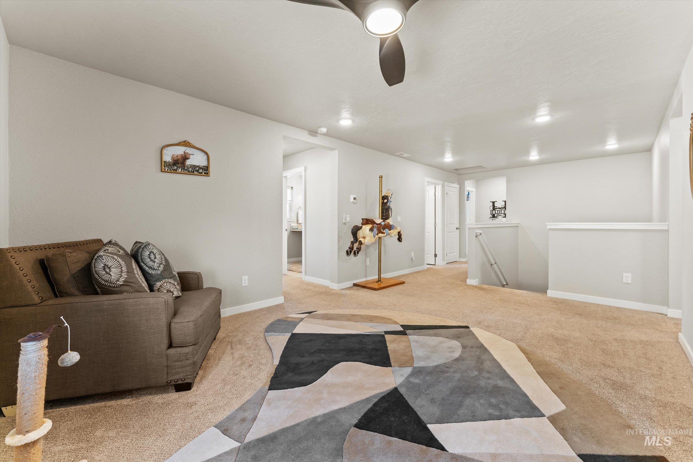 Carpeted living area with baseboards and ceiling fan