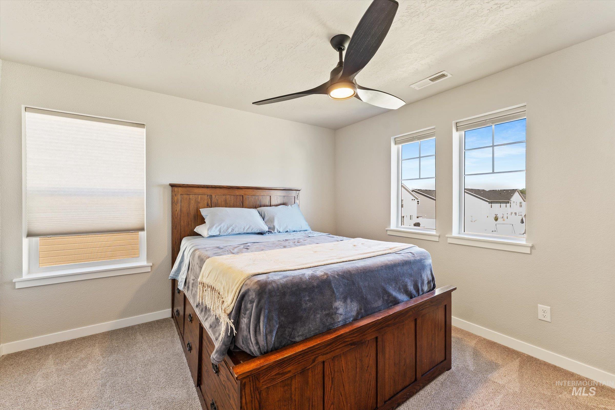Bedroom featuring light colored carpet, a ceiling fan, and a textured ceiling