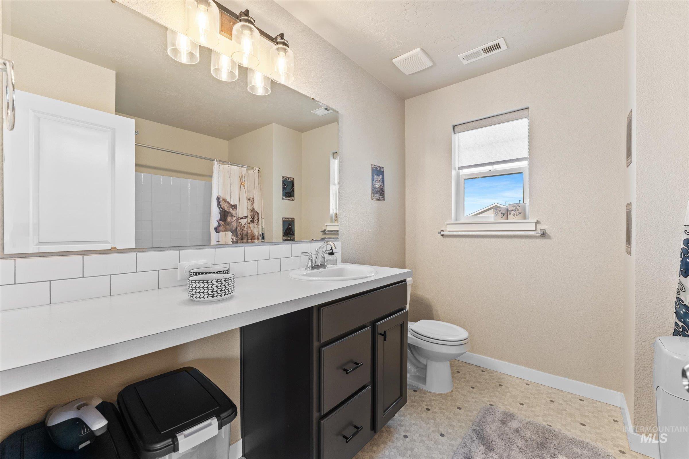 Full bath featuring vanity, a shower with curtain, and tasteful backsplash
