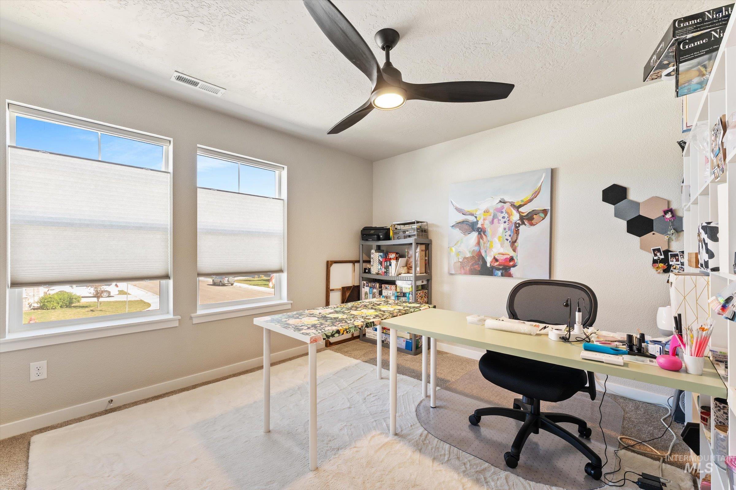 Home office featuring light carpet, a textured ceiling, and ceiling fan