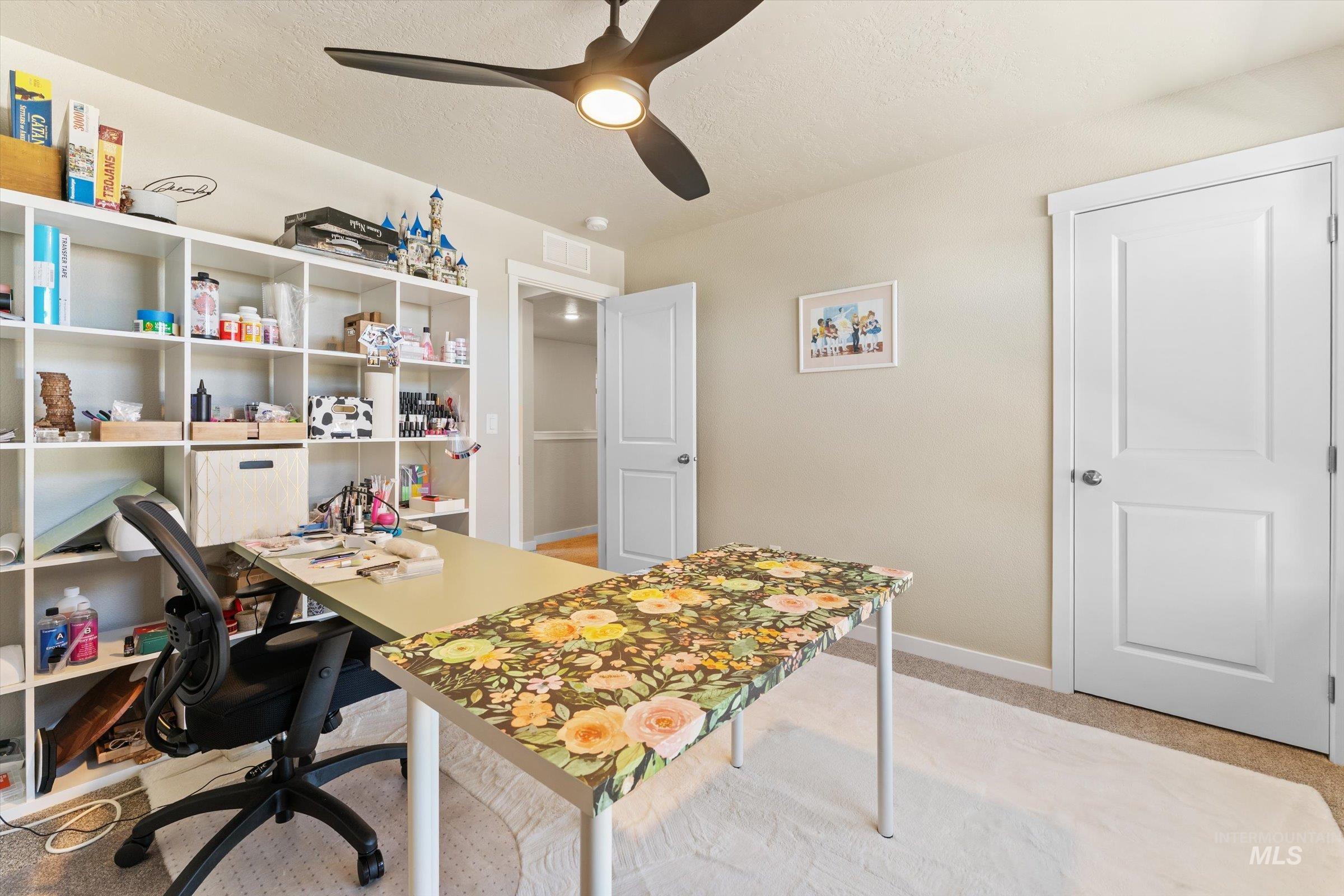 Office area with light colored carpet, a ceiling fan, and a textured ceiling