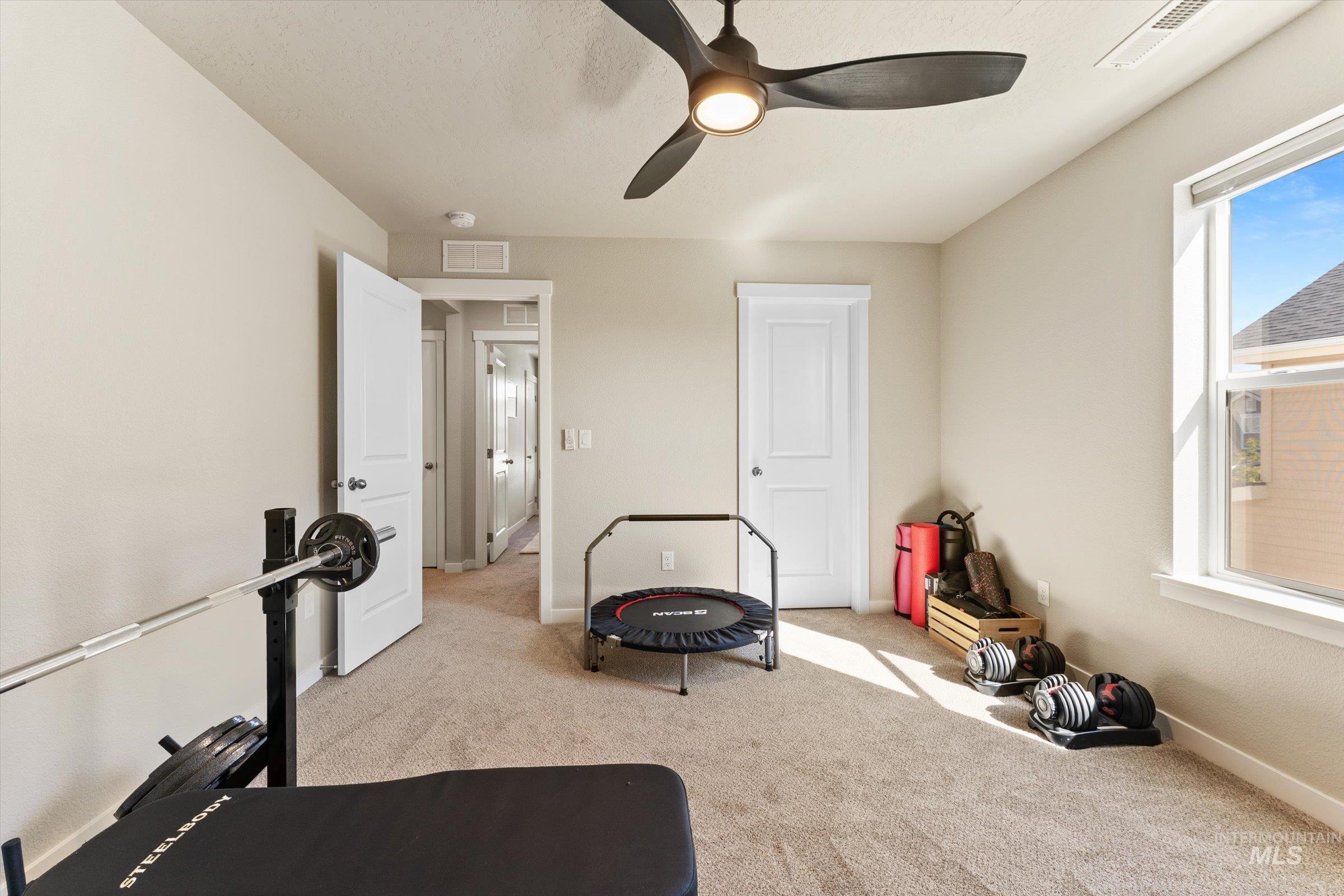 Workout room featuring light carpet and a ceiling fan