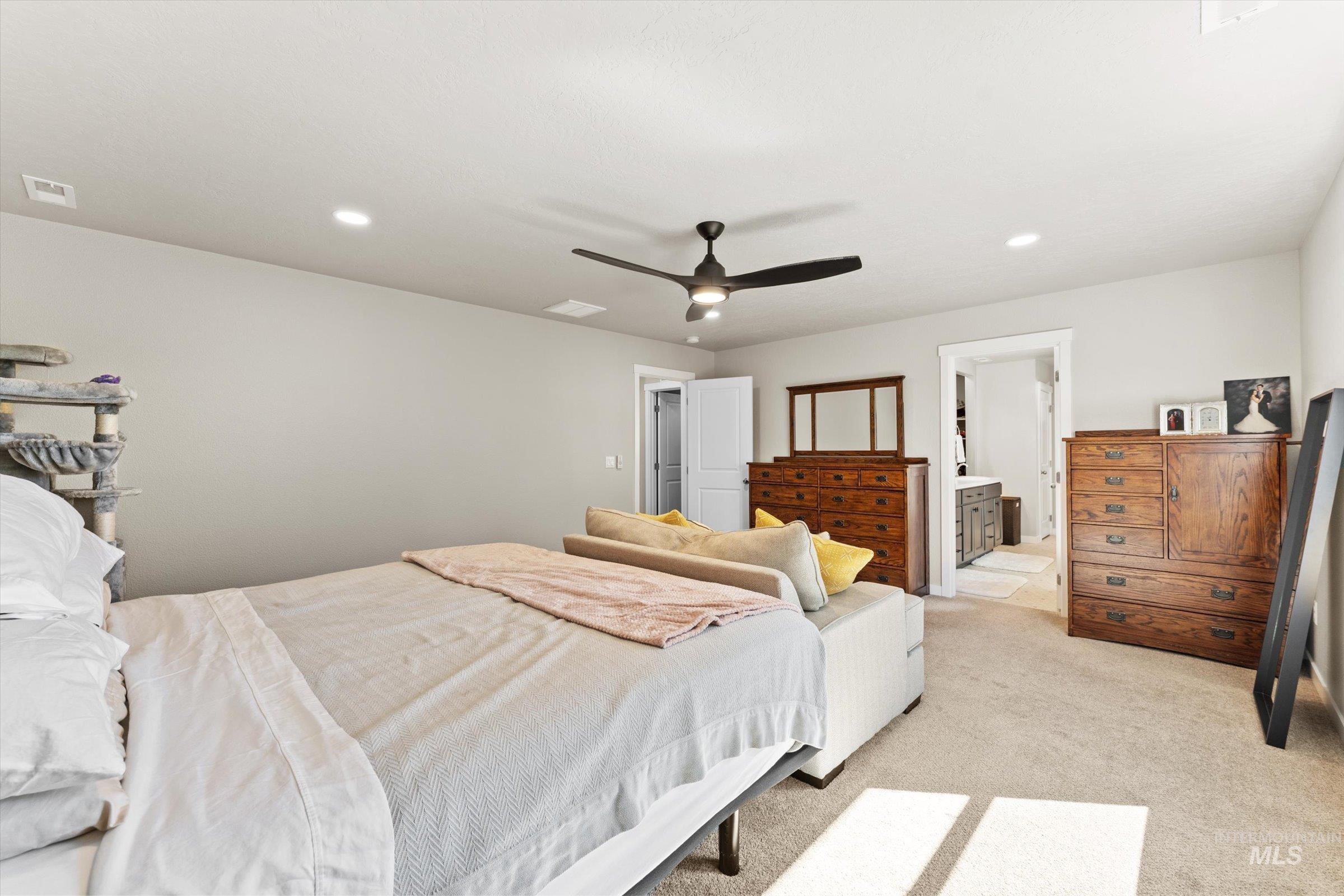 Carpeted bedroom with ensuite bathroom, recessed lighting, and a ceiling fan