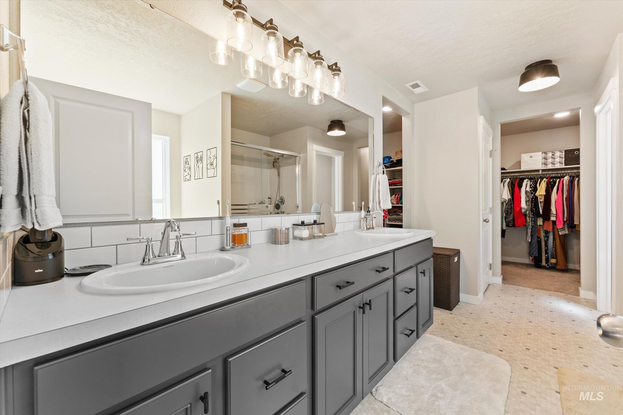 Bathroom featuring a walk in closet, a stall shower, and double vanity