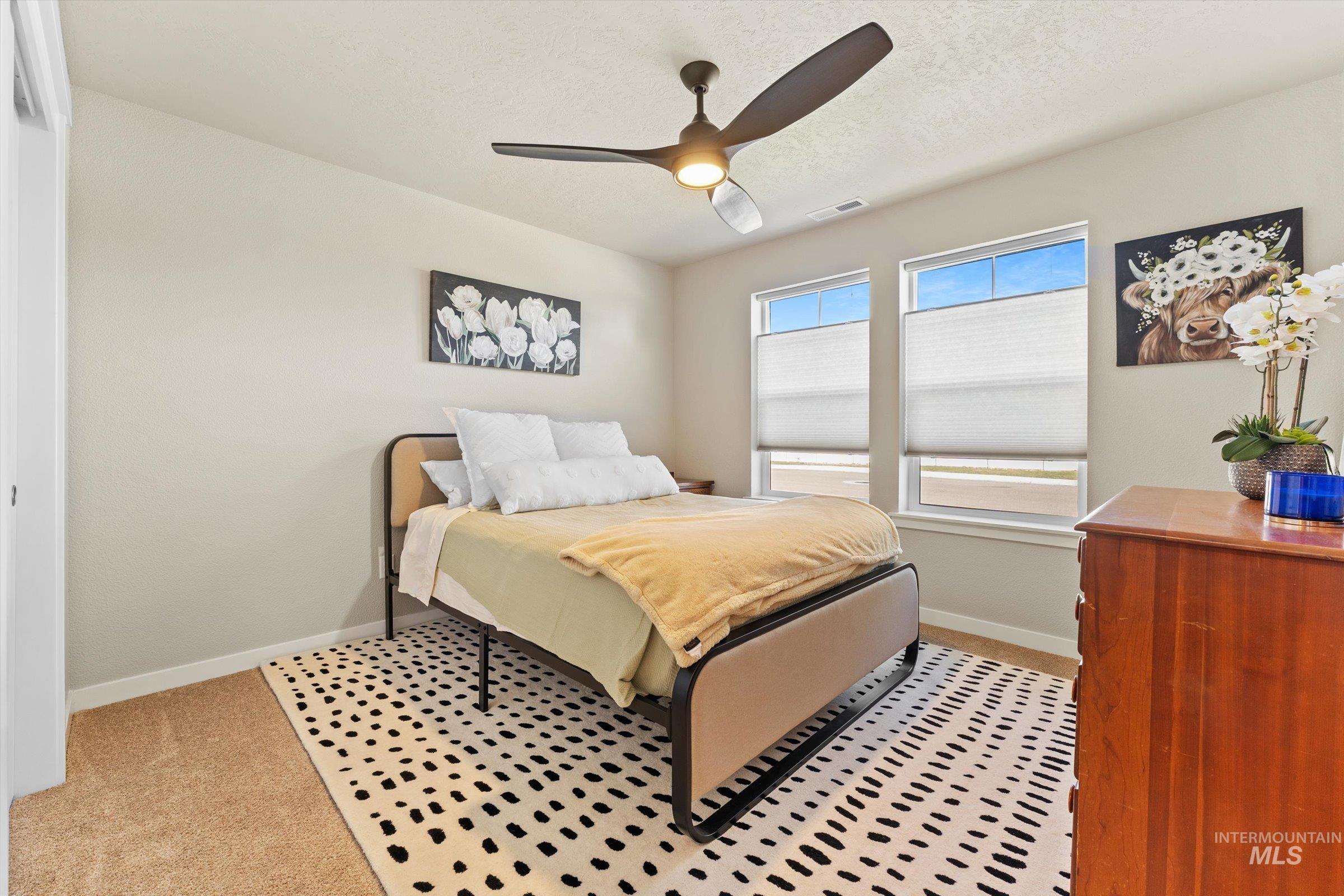 Bedroom with a textured ceiling, ceiling fan, and light carpet