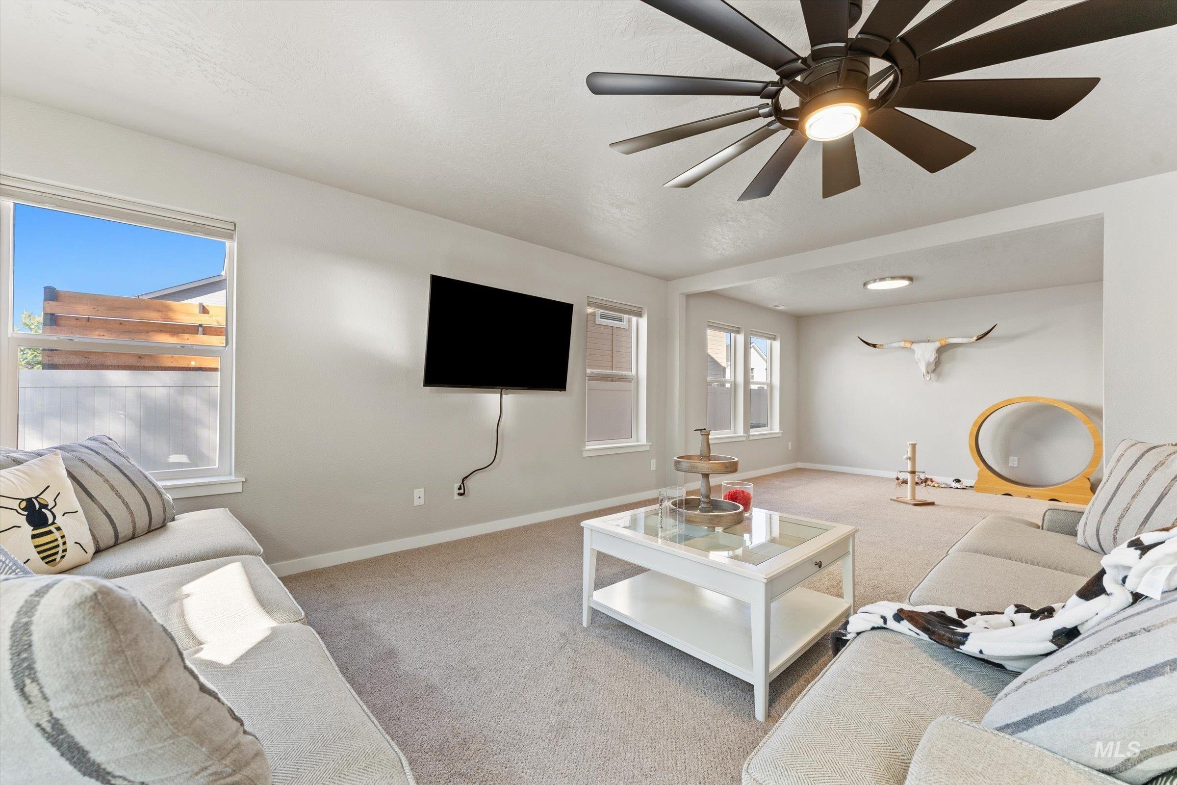 Carpeted living area with baseboards and ceiling fan