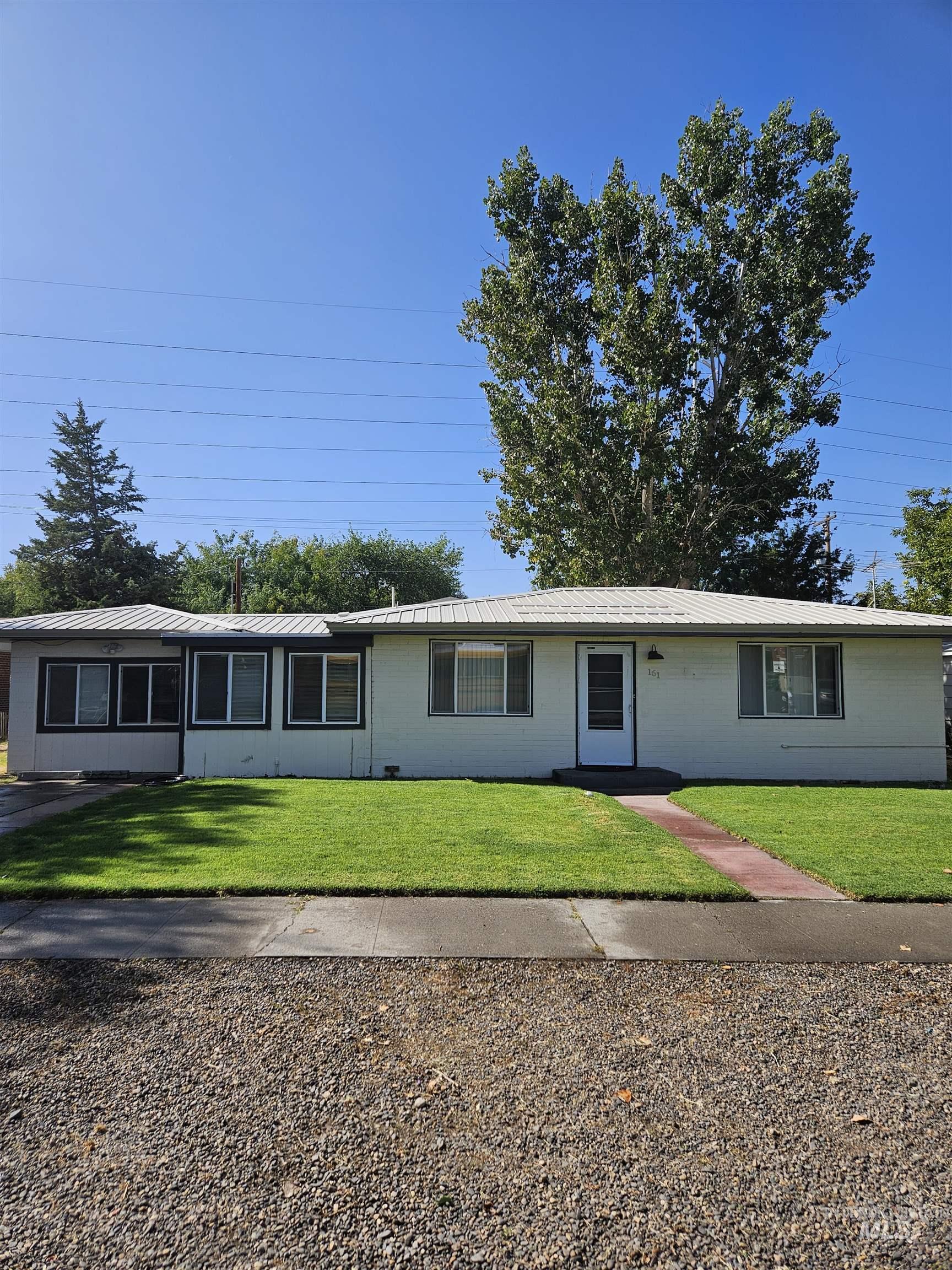 Ranch-style house featuring a metal roof and a front lawn