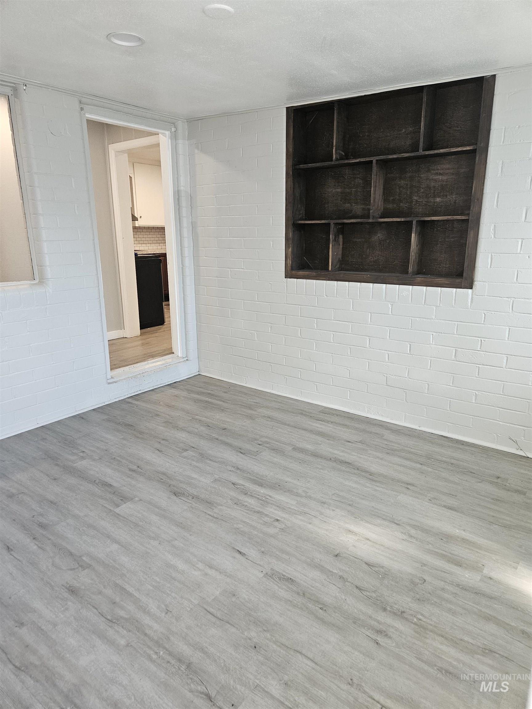 Empty room with wood finished floors and brick wall