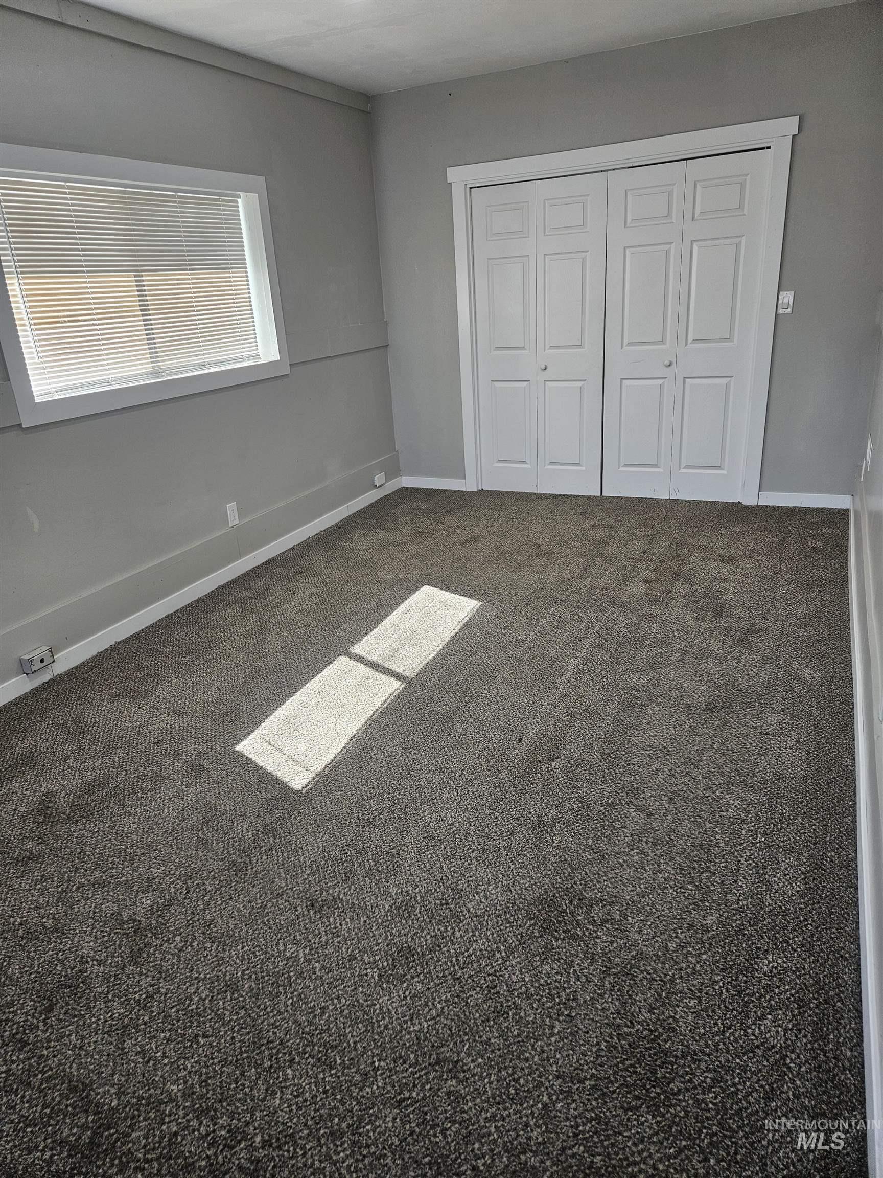 Unfurnished bedroom featuring dark carpet and a closet