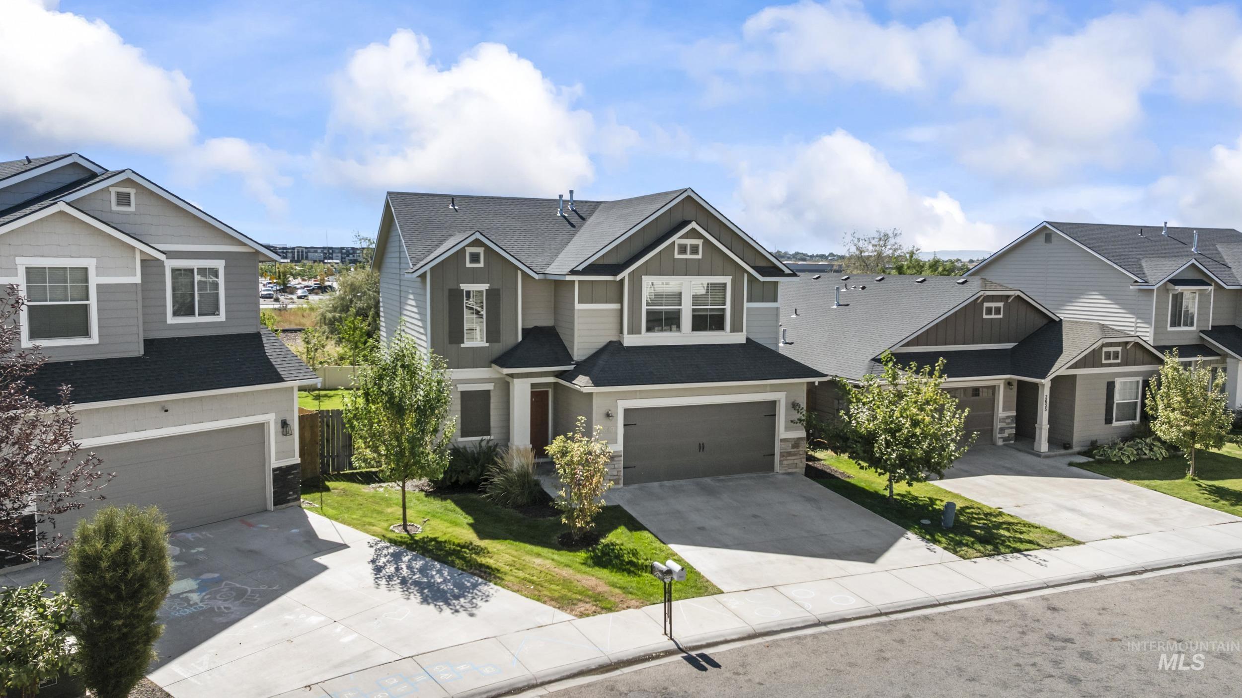 Craftsman inspired home with stone siding, roof with shingles, concrete driveway, and a residential view