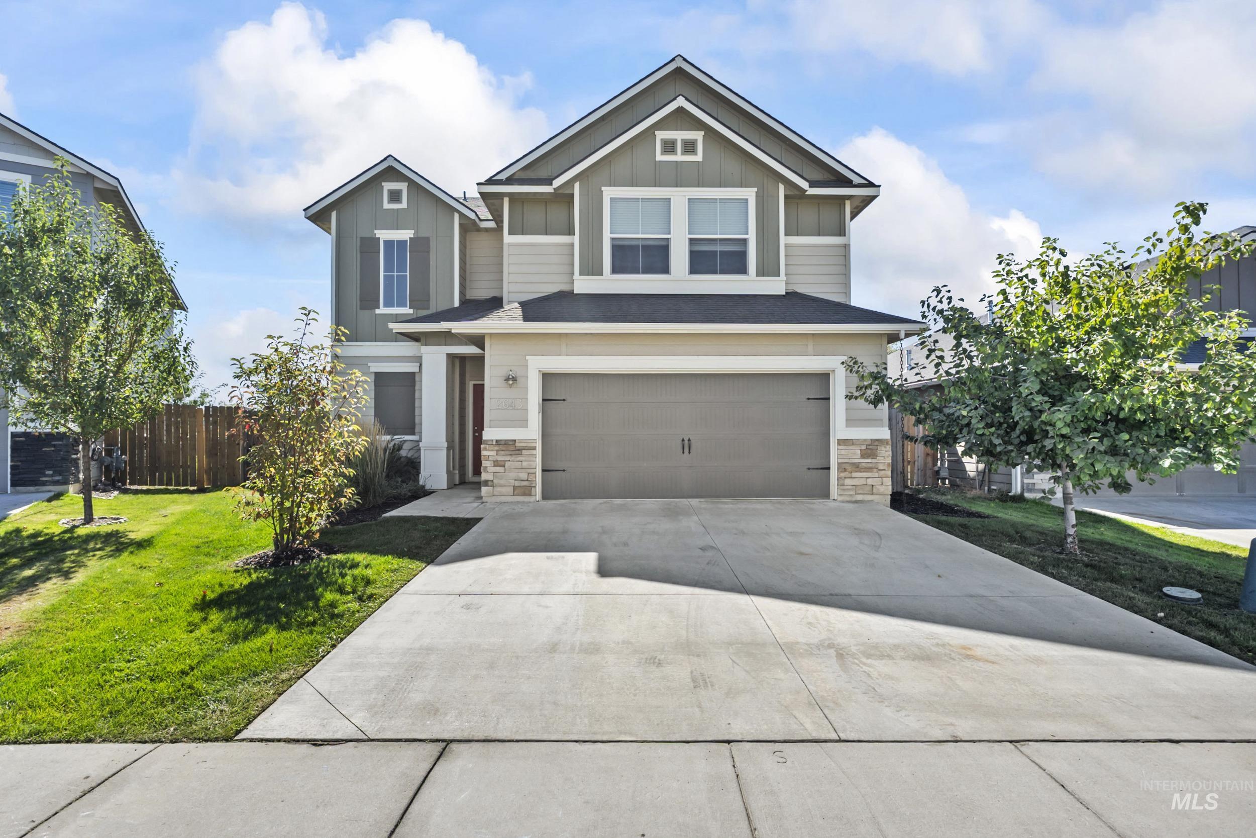 Craftsman house featuring board and batten siding, stone siding, a garage, and driveway