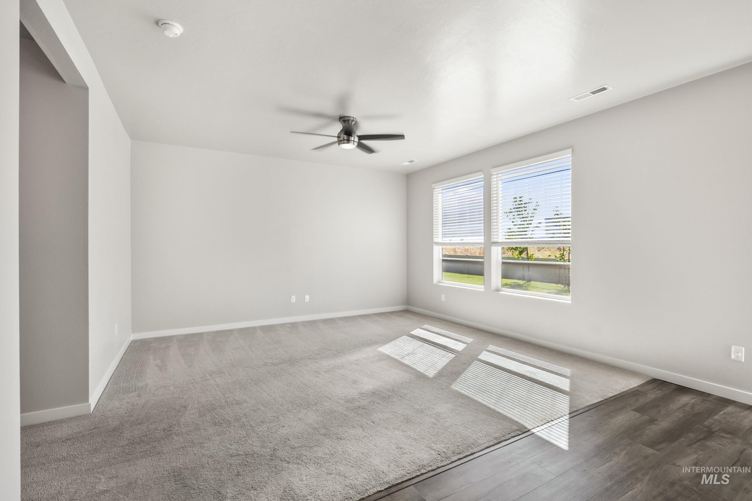 Carpeted spare room with baseboards and a ceiling fan