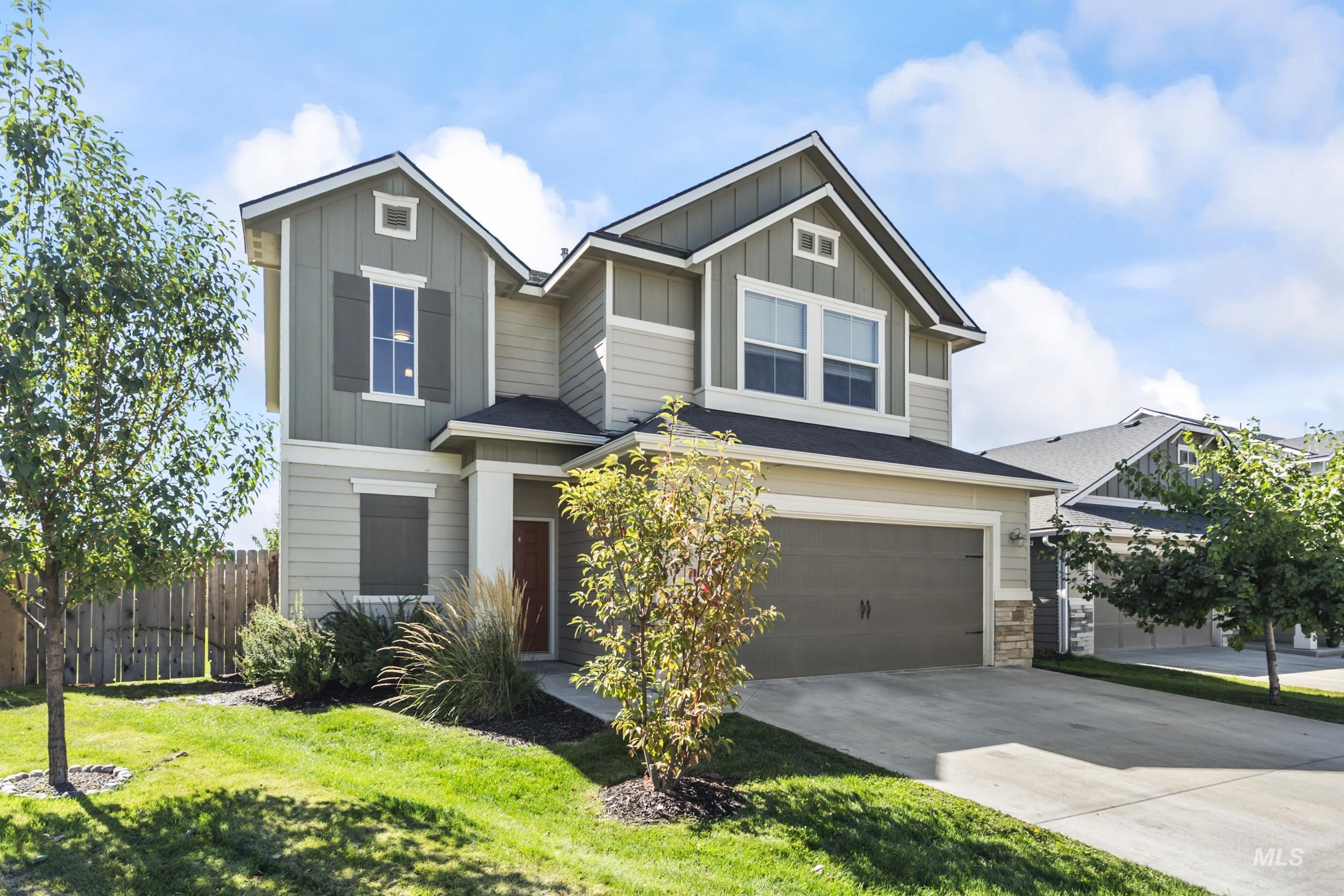 Craftsman-style home with board and batten siding, driveway, an attached garage, and stone siding