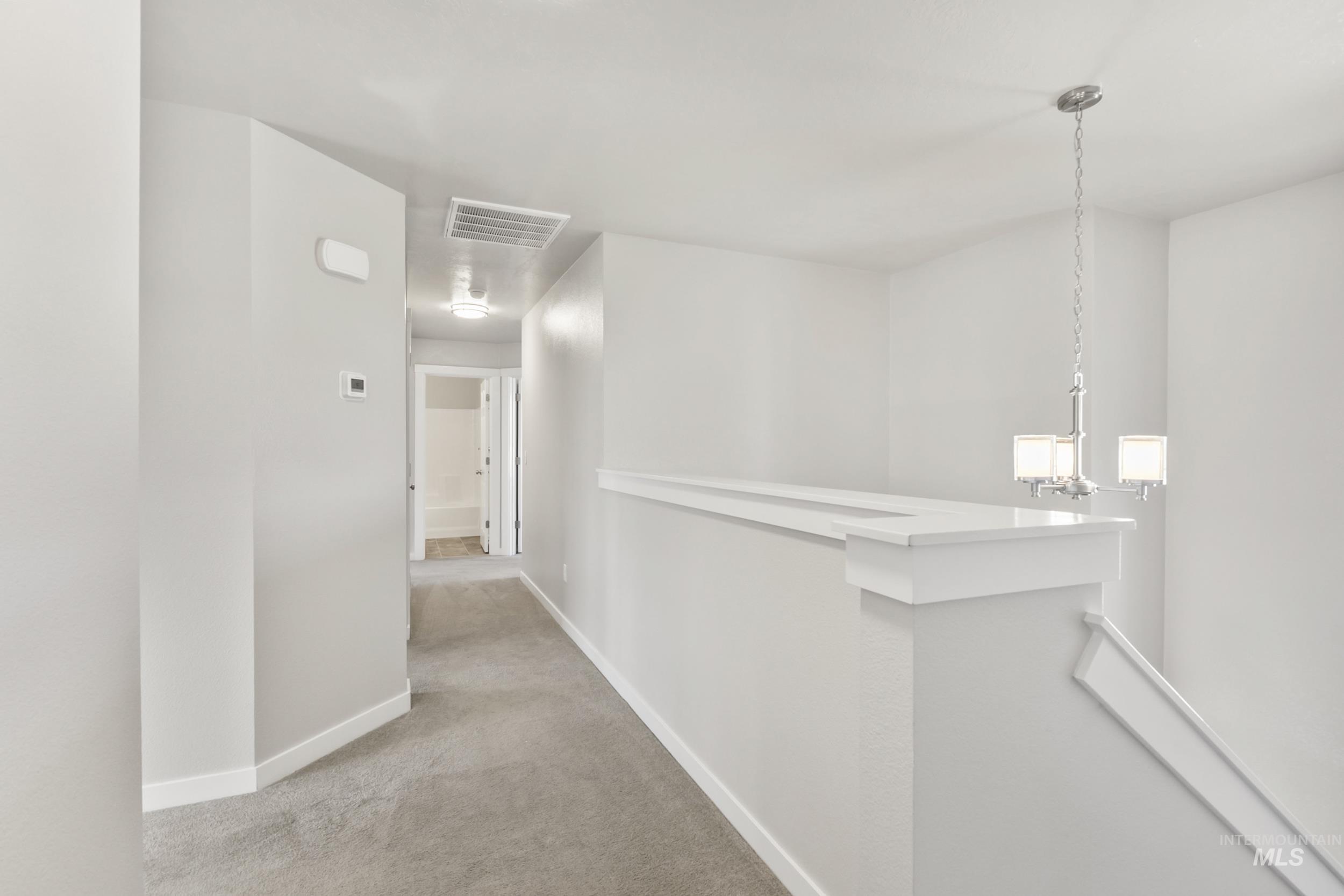 Hallway with an upstairs landing and light carpet