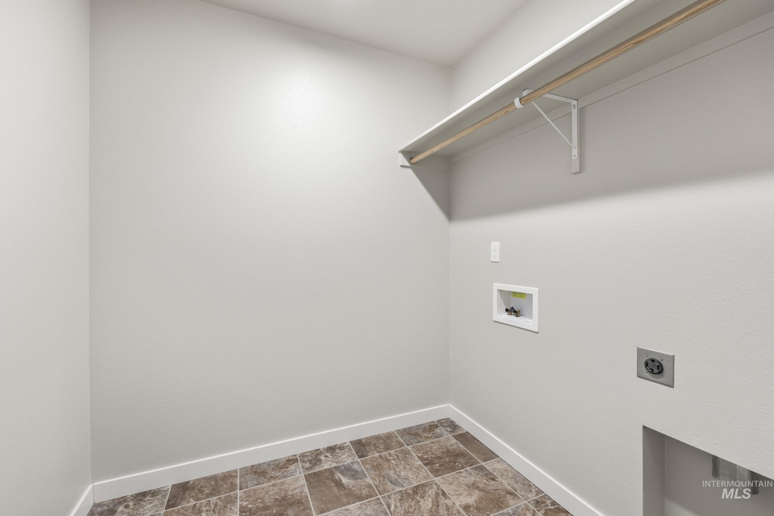 Washroom featuring hookup for an electric dryer, hookup for a washing machine, and stone finish floors