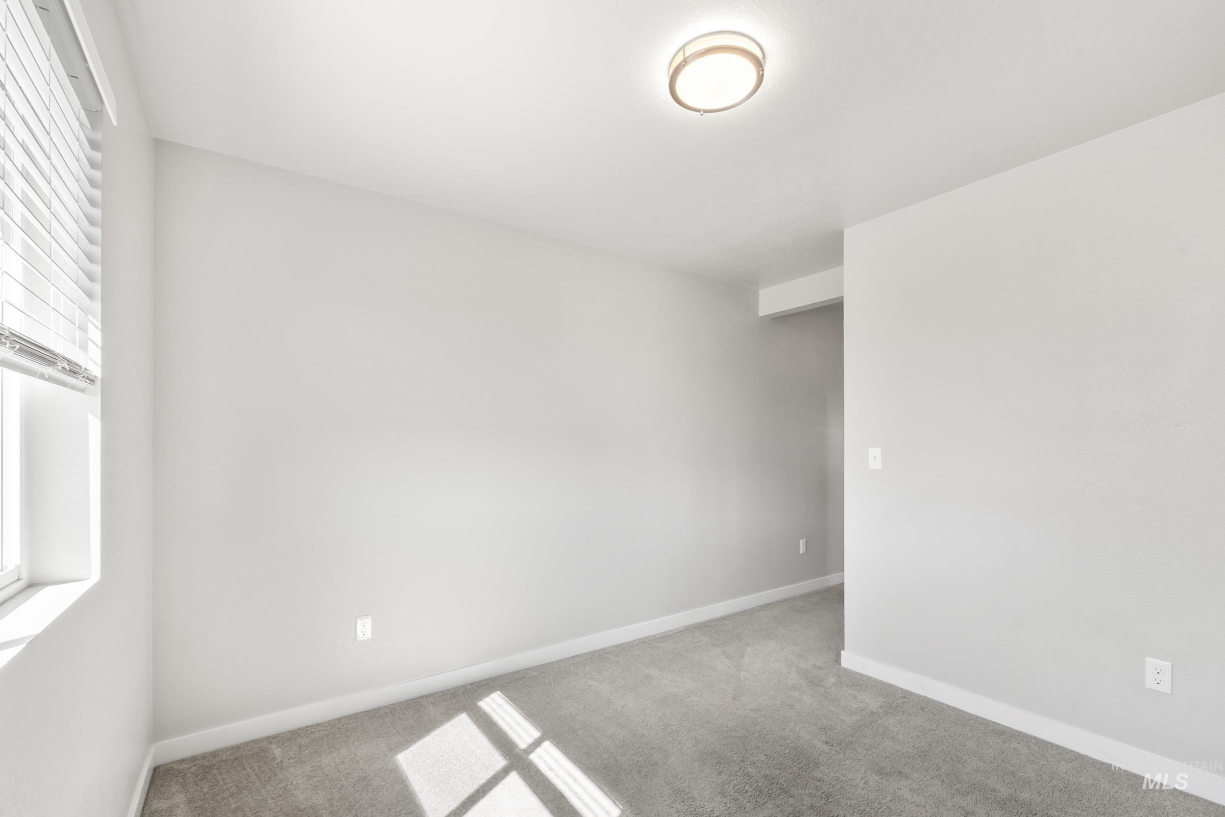 Carpeted spare room featuring baseboards