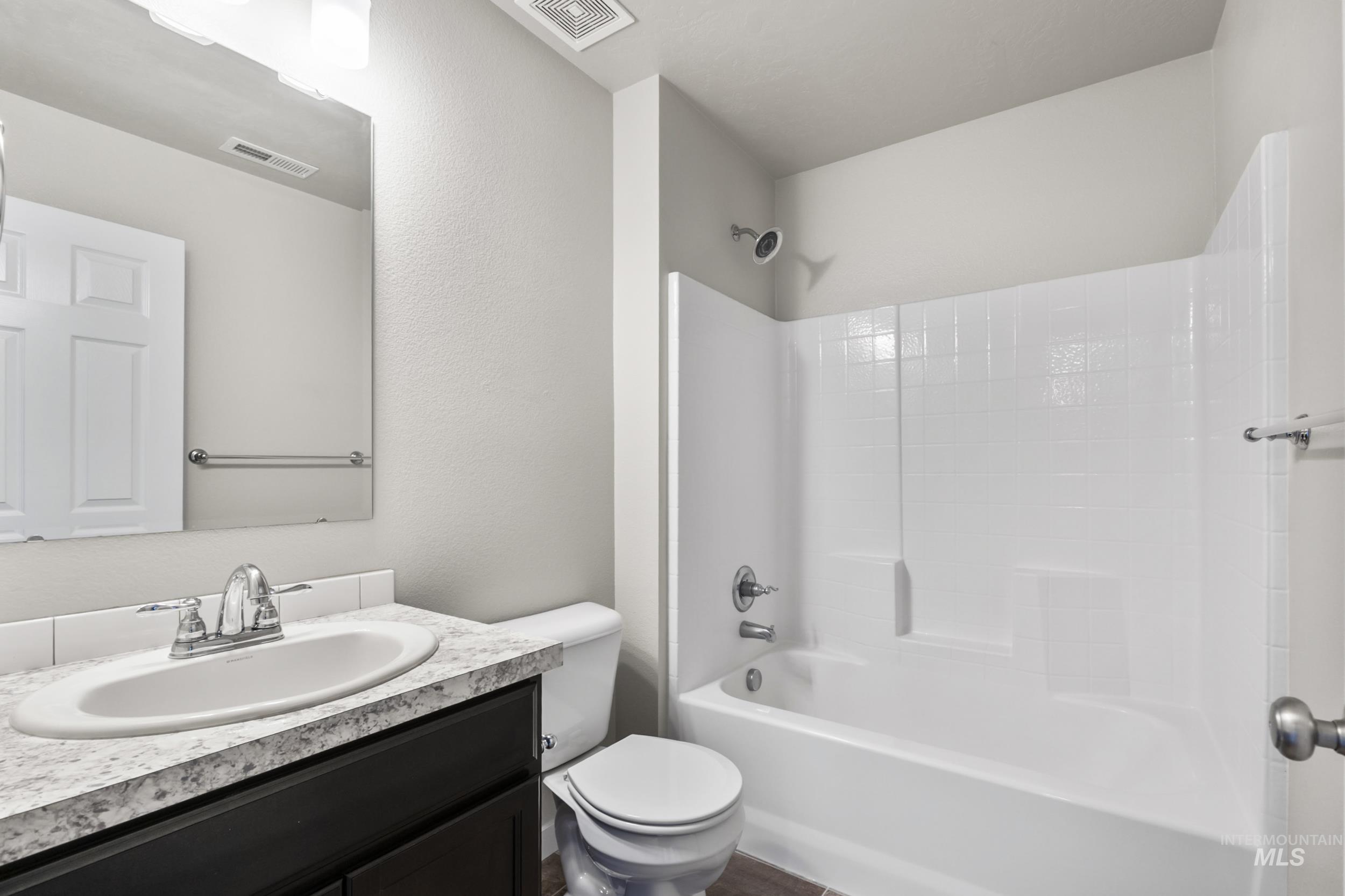 Full bathroom with bathing tub / shower combination, vanity, and a textured wall