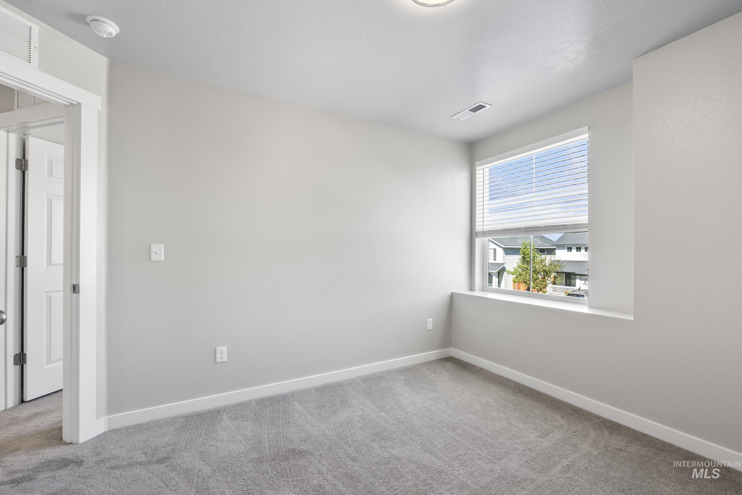 Spare room with baseboards and light colored carpet