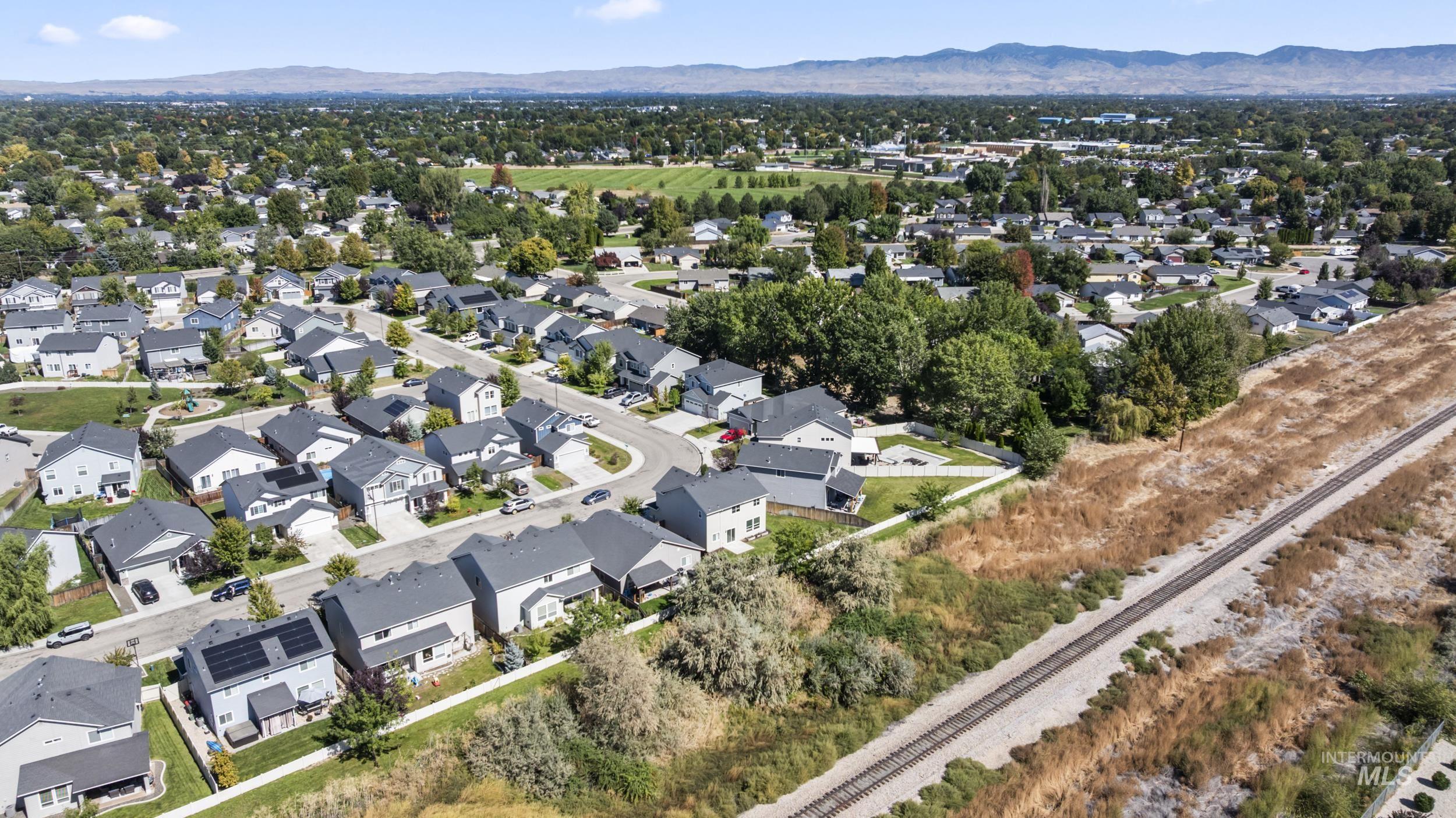 Aerial view of property and surrounding area featuring a mountainous background and nearby suburban area