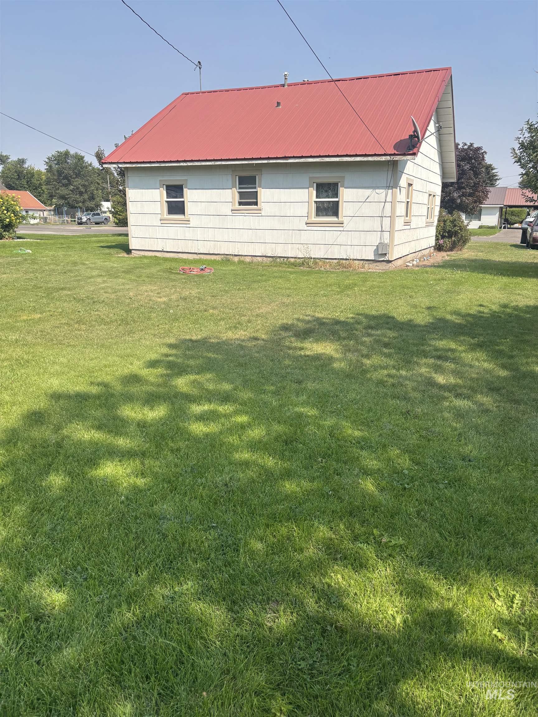 View of side of property with a yard and a metal roof