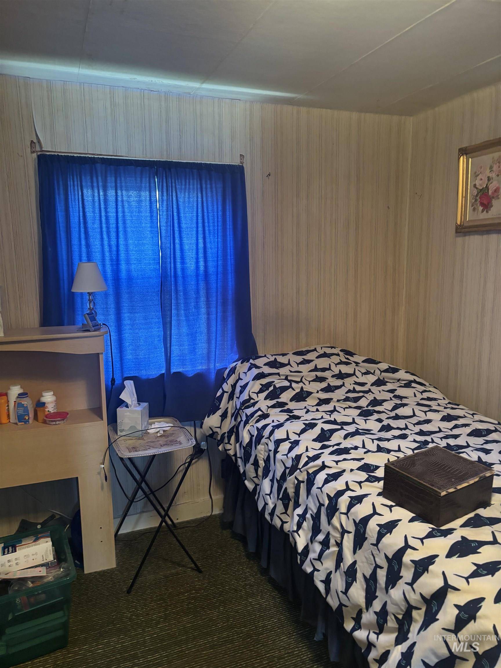Bedroom featuring dark colored carpet and wood walls