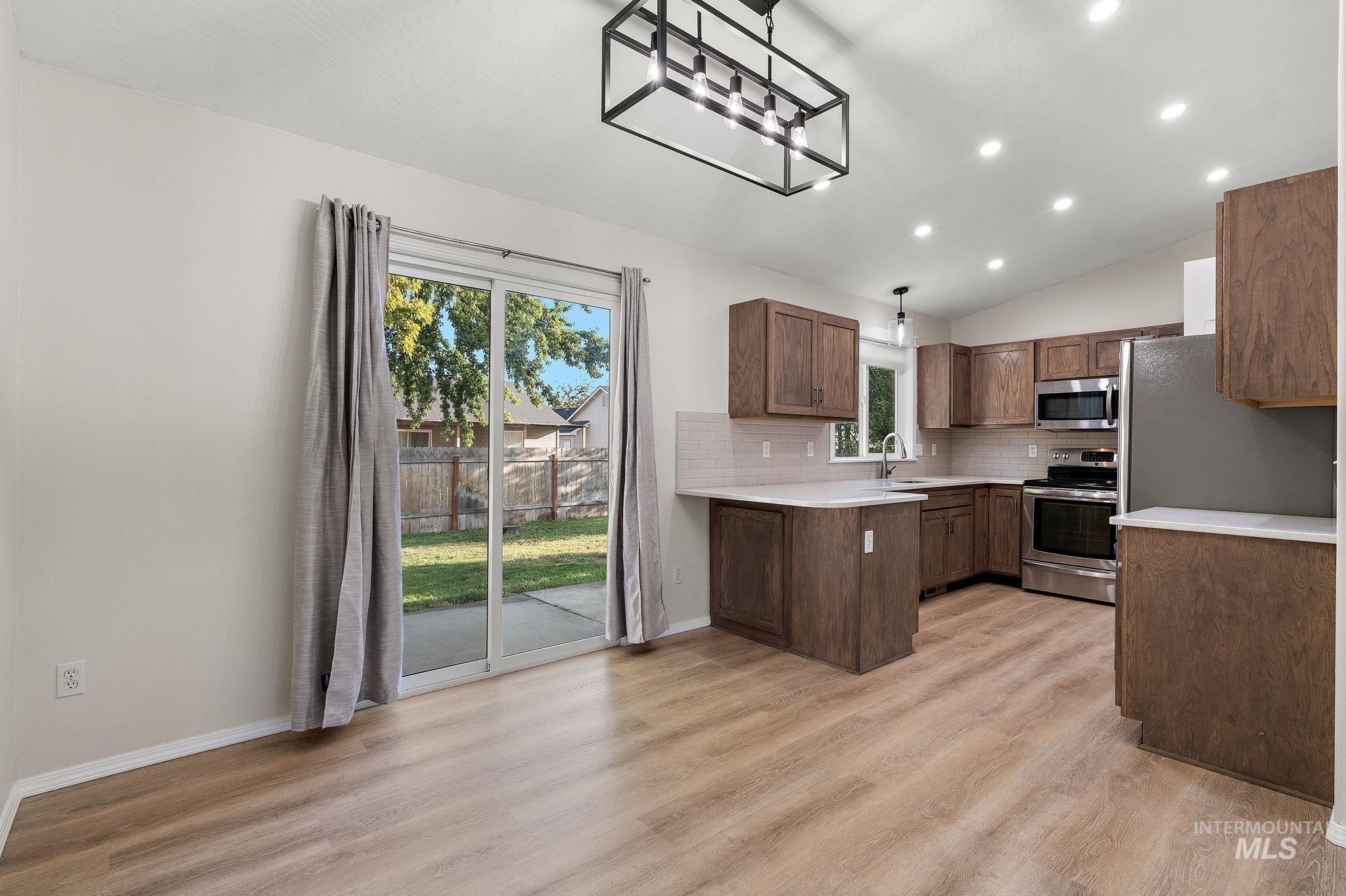 Kitchen featuring lofted ceiling, stainless steel appliances, recessed lighting, backsplash, and light wood-type flooring