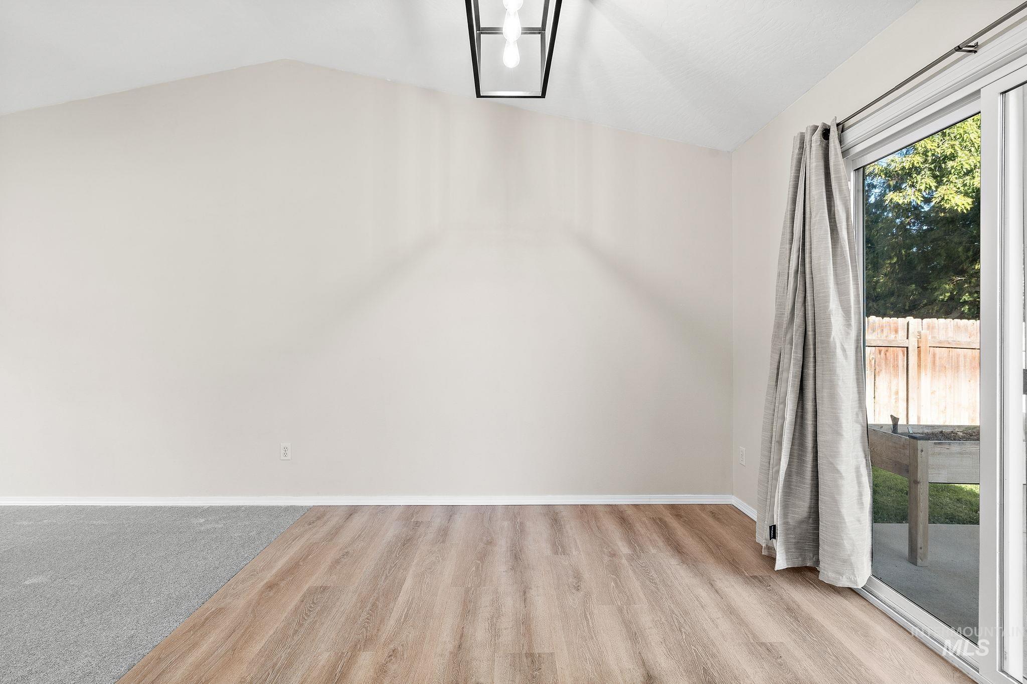 Empty room featuring light wood-style flooring and vaulted ceiling