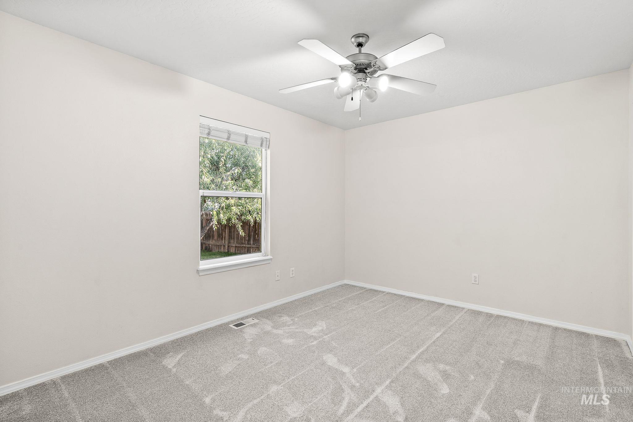 Primary room featuring light colored carpet and a ceiling fan