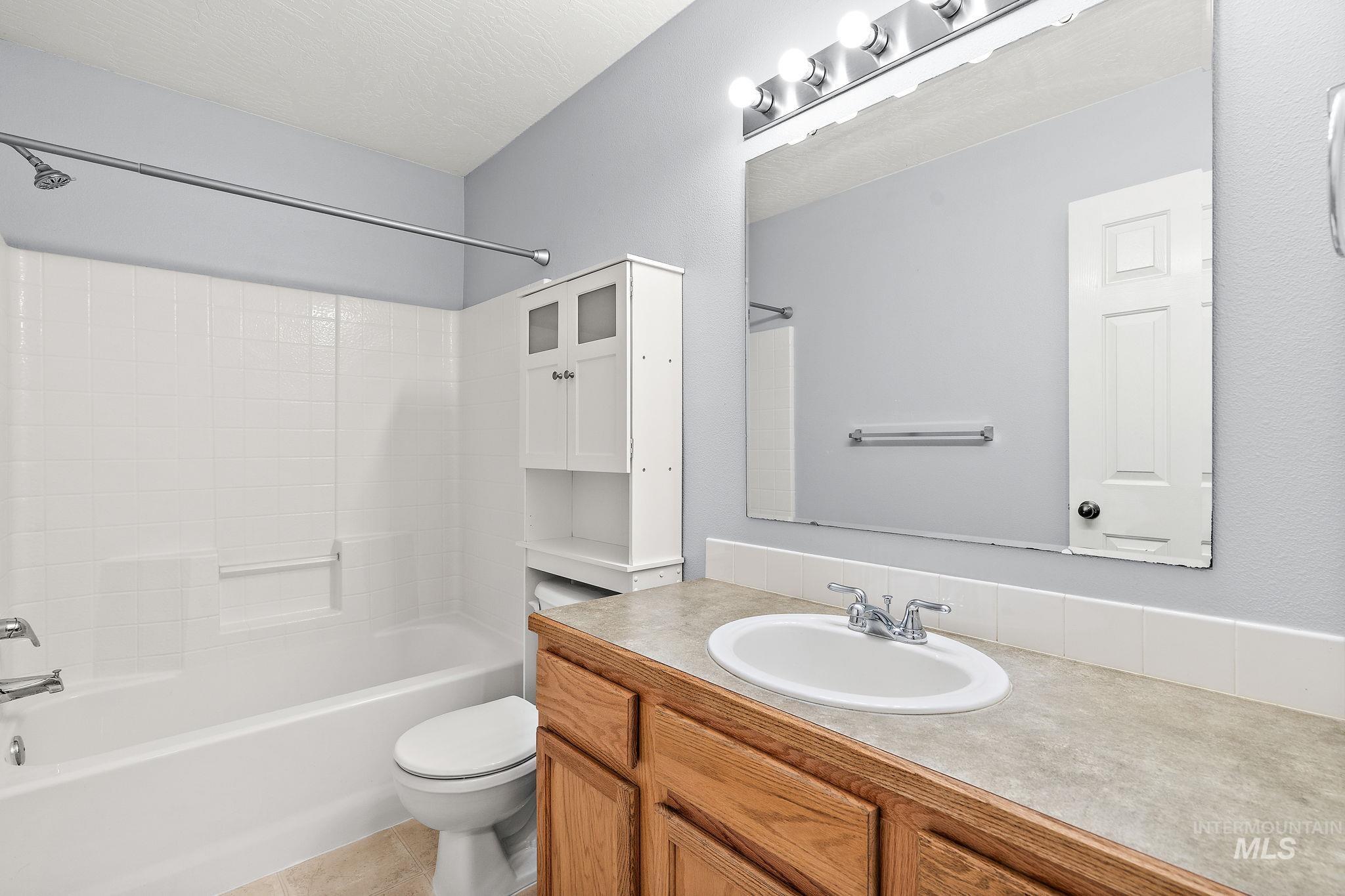 Bathroom with shower / tub combination, vanity, light tile patterned floors, and a textured ceiling