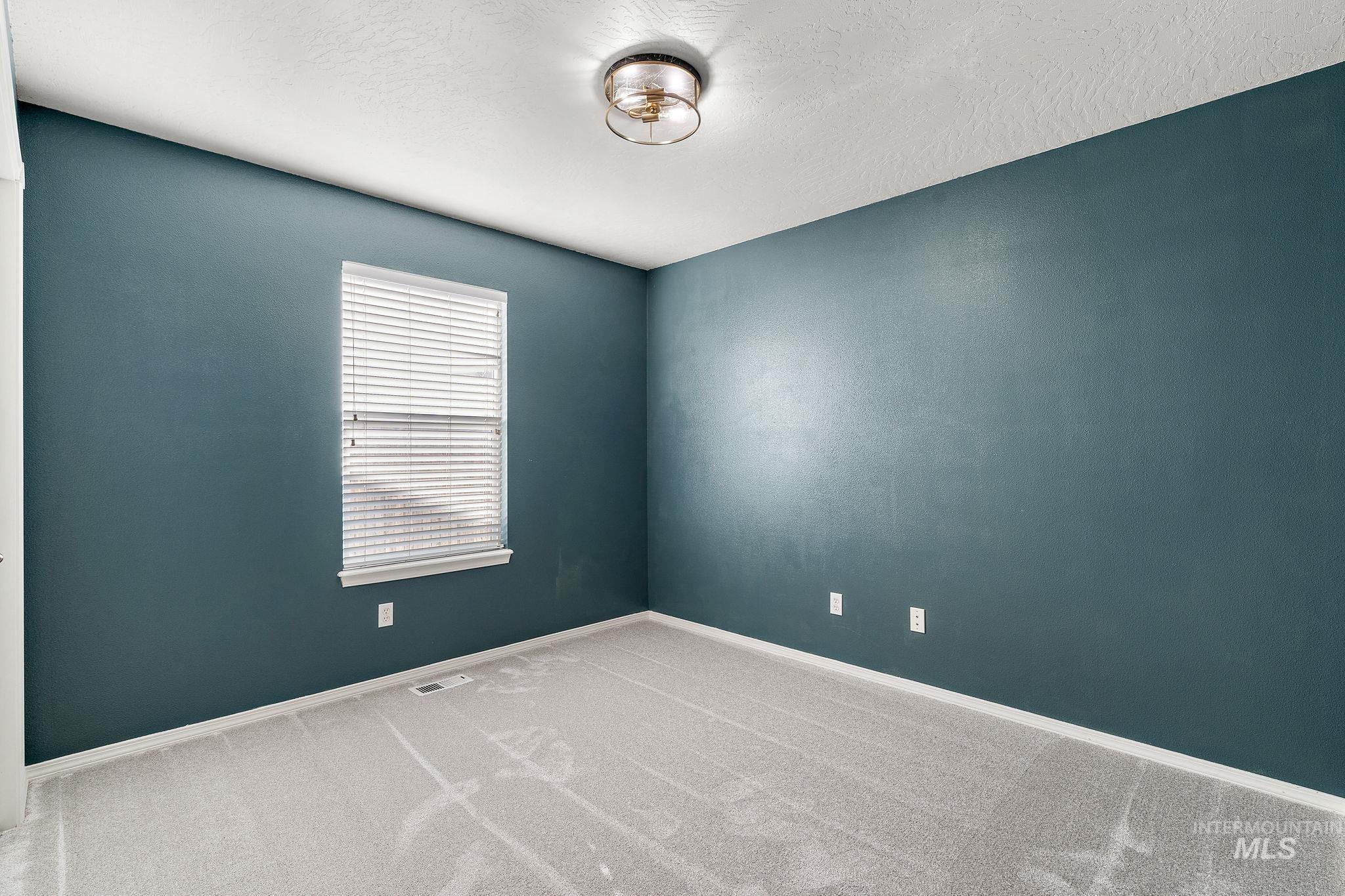 Carpeted spare room with baseboards and a textured ceiling