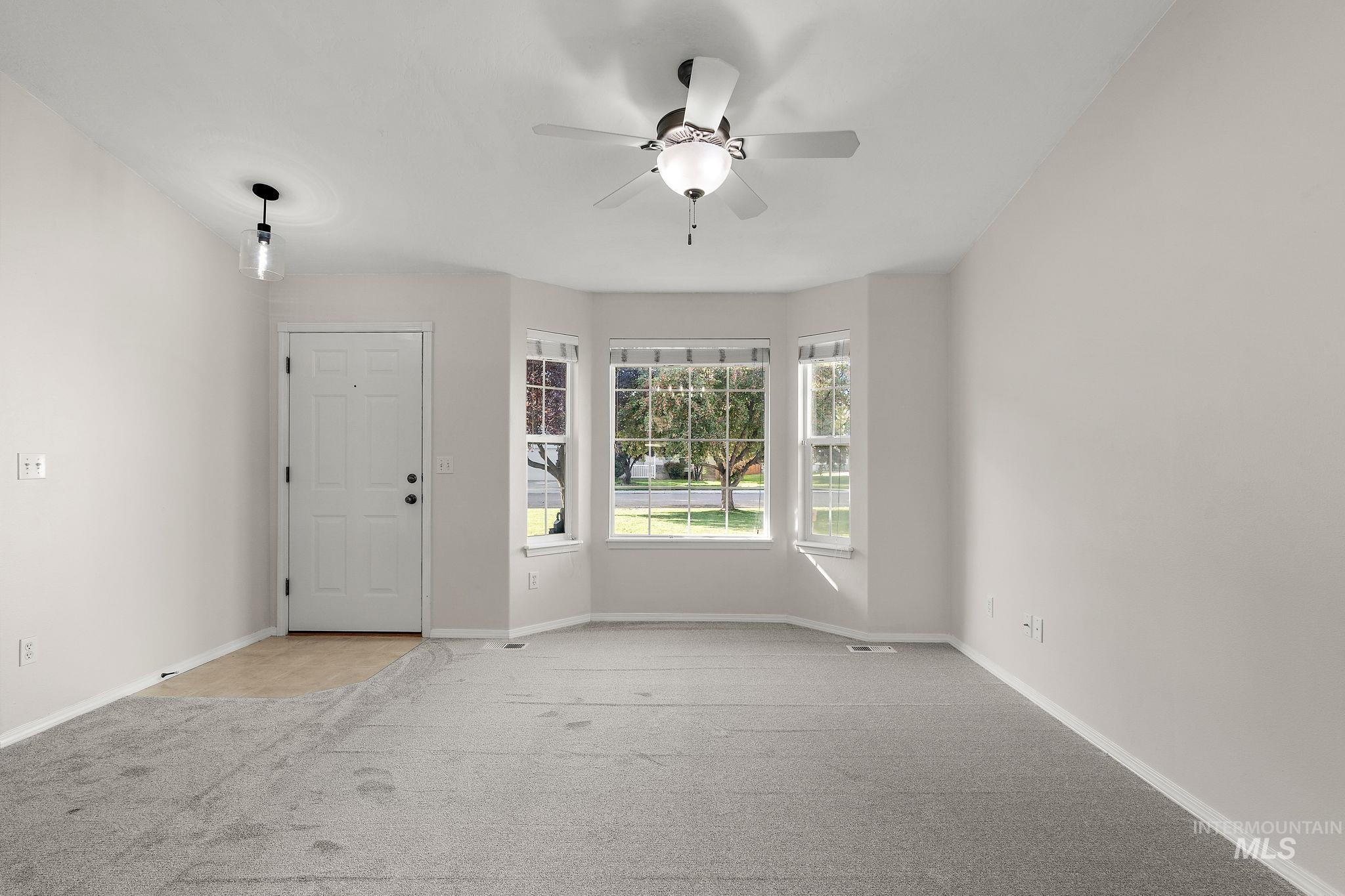 Empty room featuring light carpet and ceiling fan