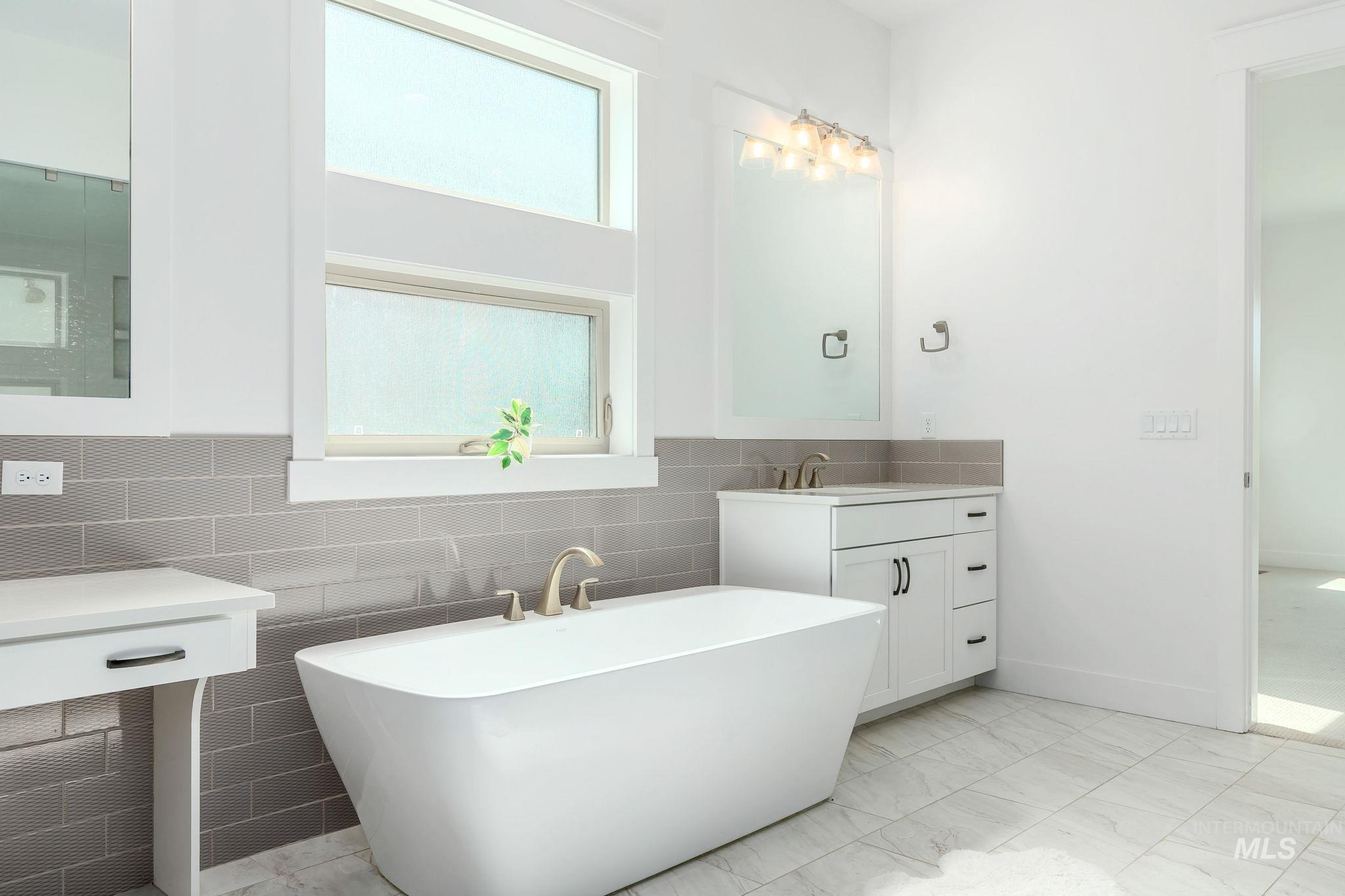 Bathroom with a freestanding bath, vanity, and tile walls