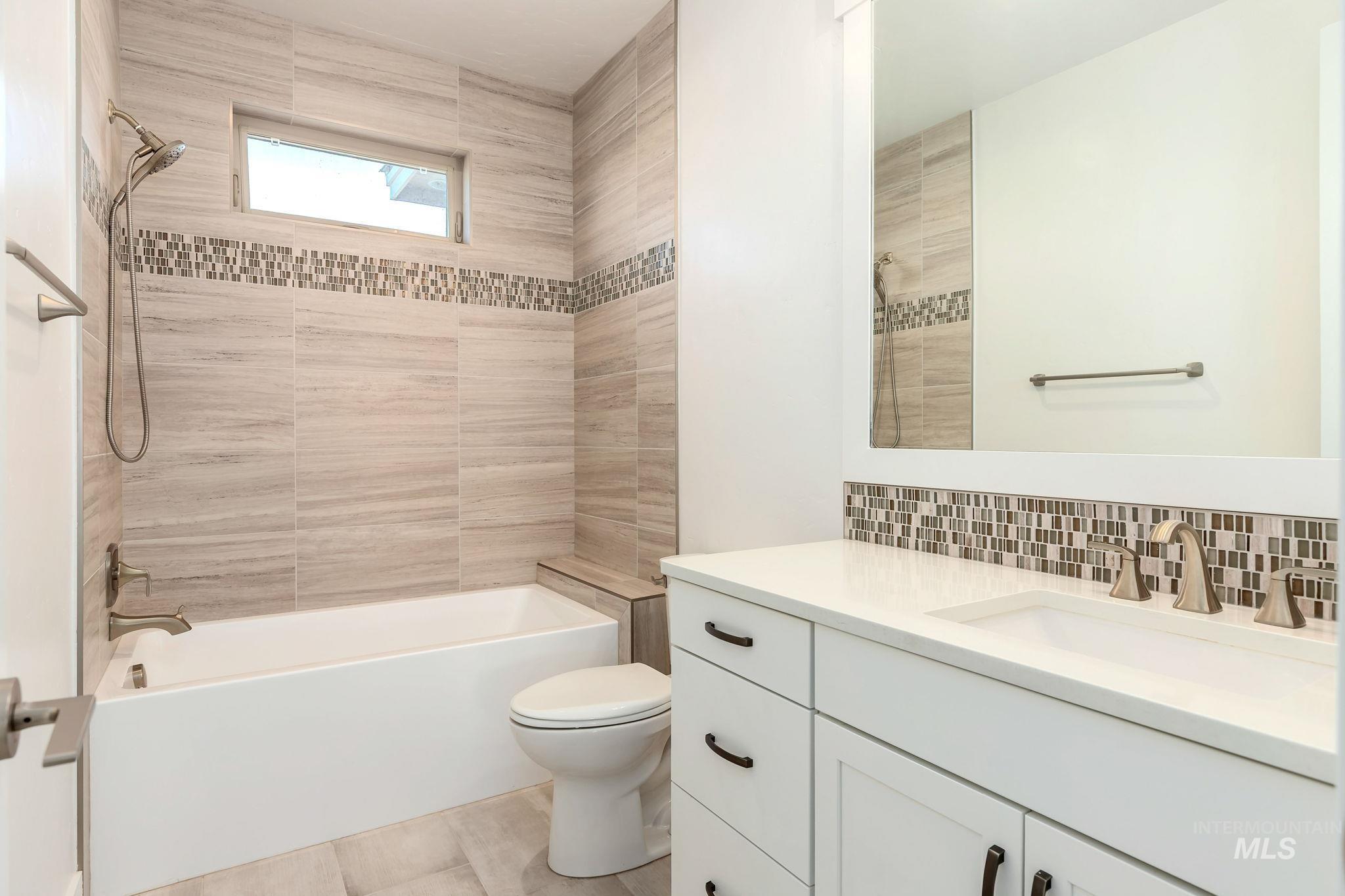 Full bathroom with washtub / shower combination, vanity, and tasteful backsplash