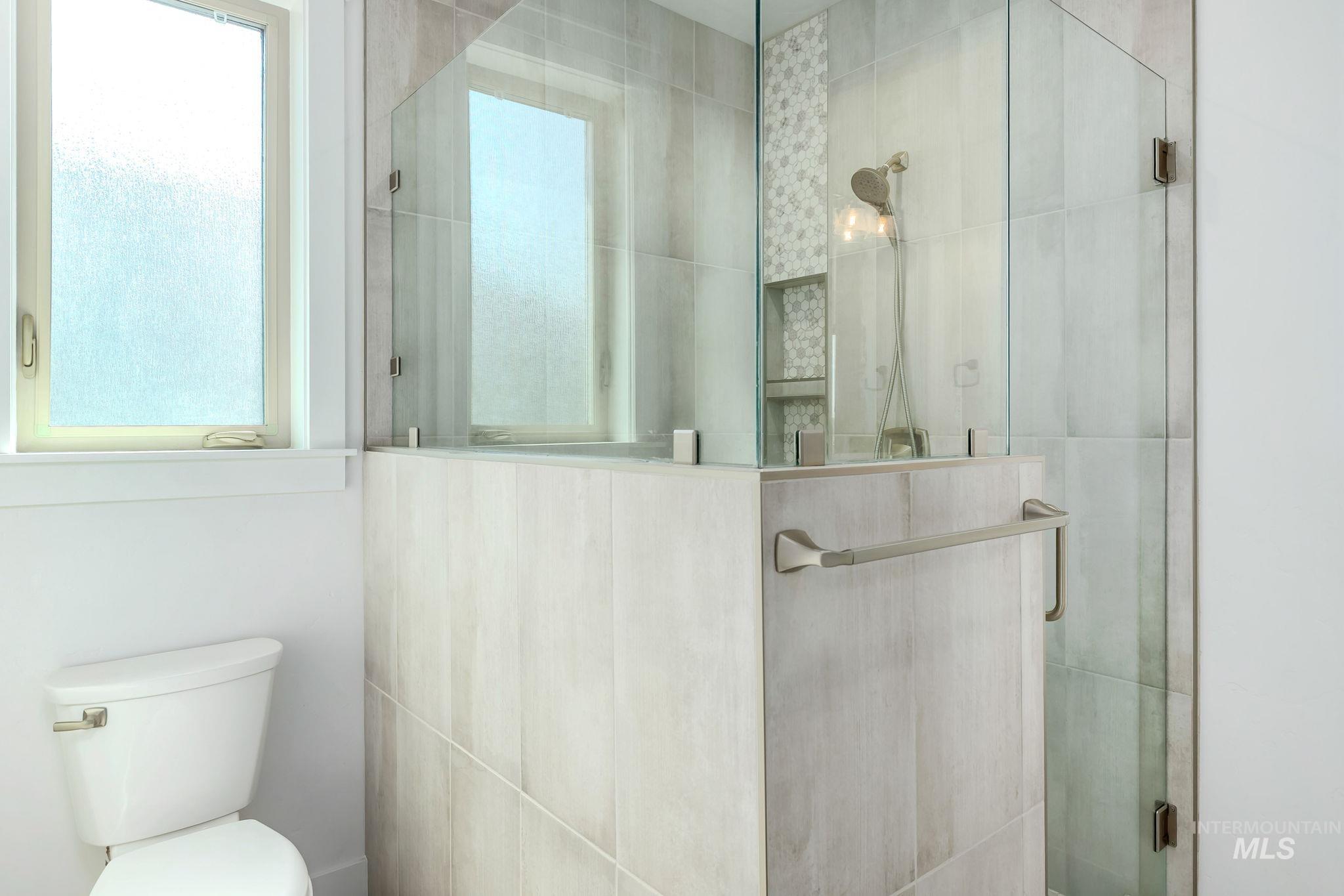 Full bath featuring a shower stall and toilet