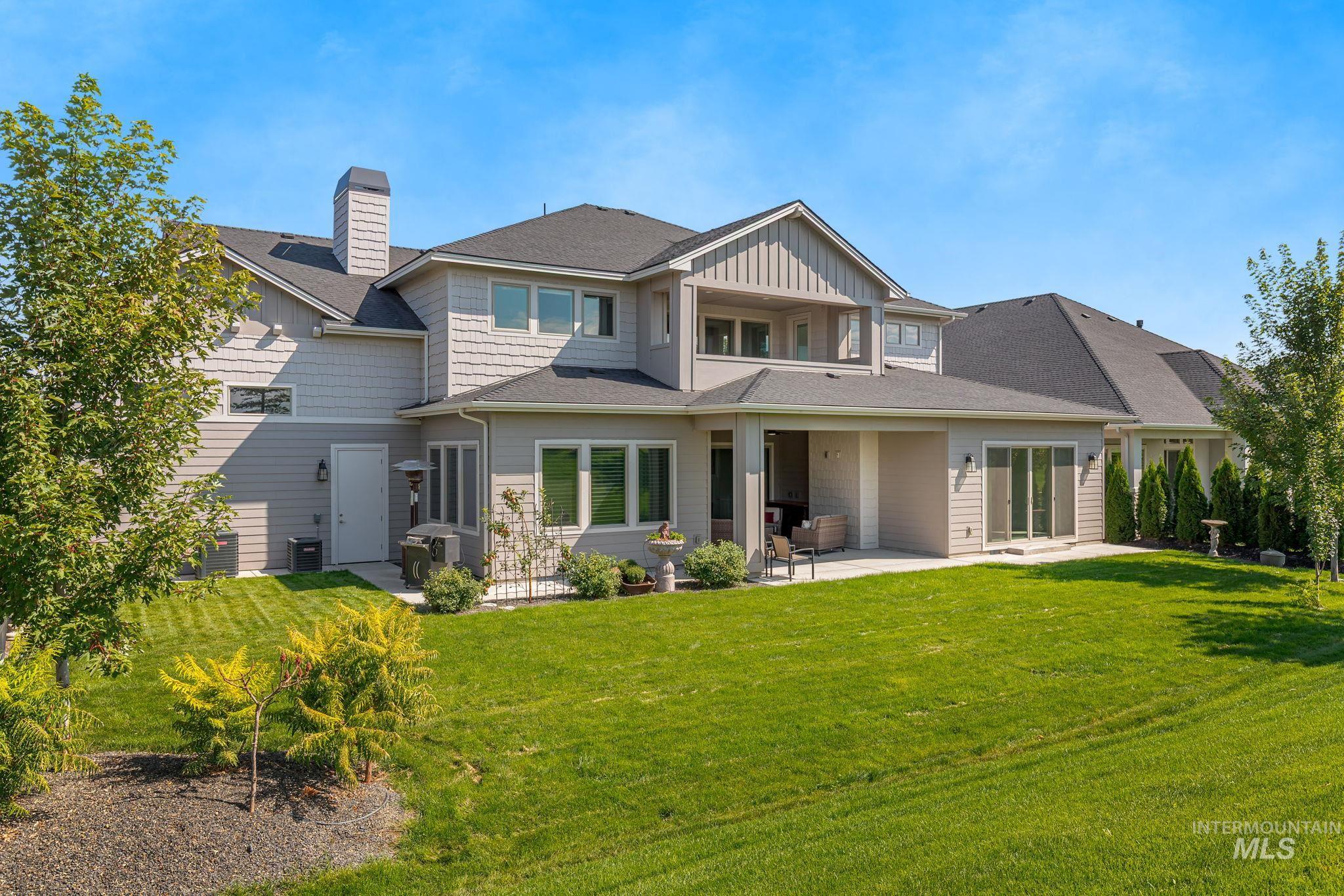 Back of house with a patio, a balcony, board and batten siding, a yard, and a chimney