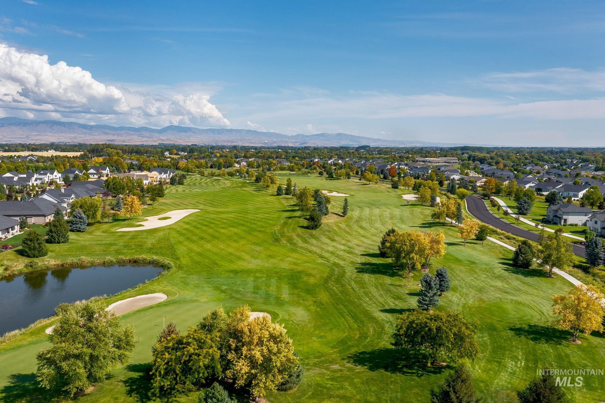 Aerial view of property's location with nearby suburban area, a golf club, and a water and mountain view
