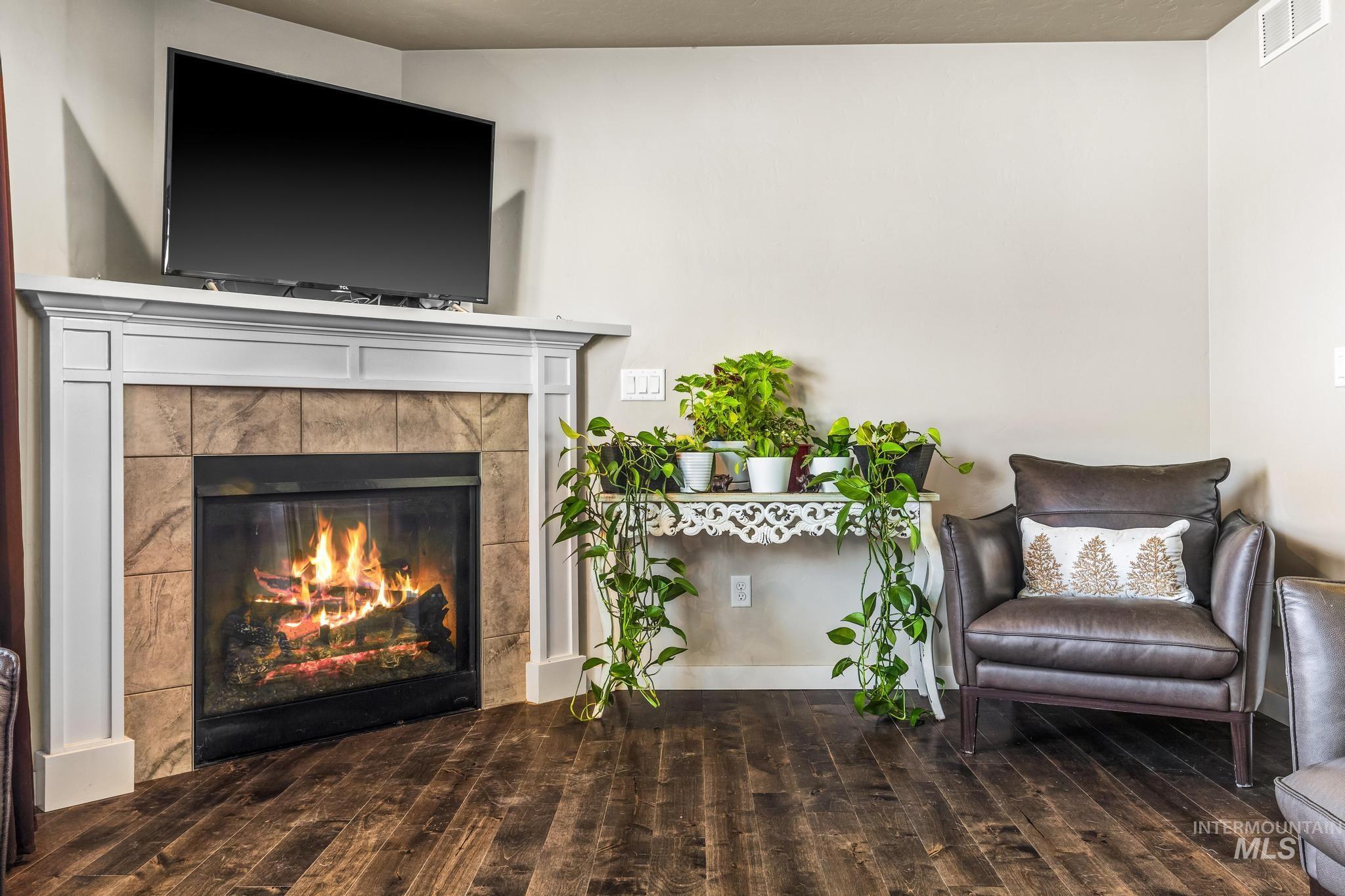 Living area with dark wood finished floors and a tiled fireplace