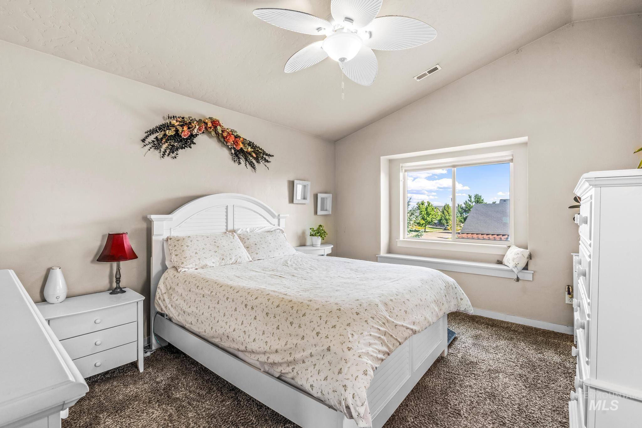 Bedroom with vaulted ceiling, dark carpet, and ceiling fan
