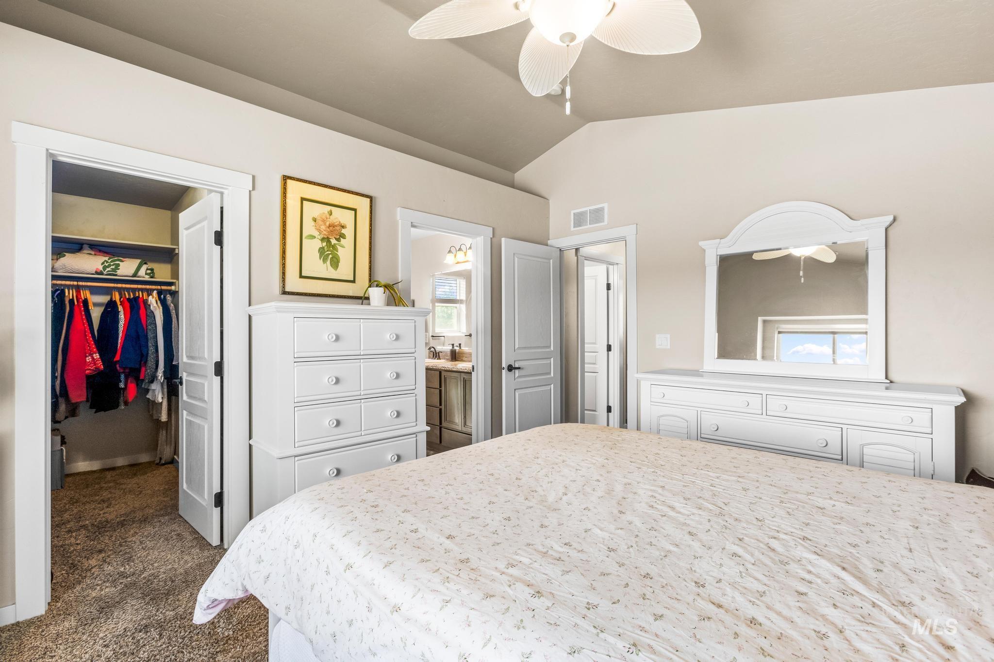 Bedroom featuring a spacious closet, lofted ceiling, dark colored carpet, and a ceiling fan
