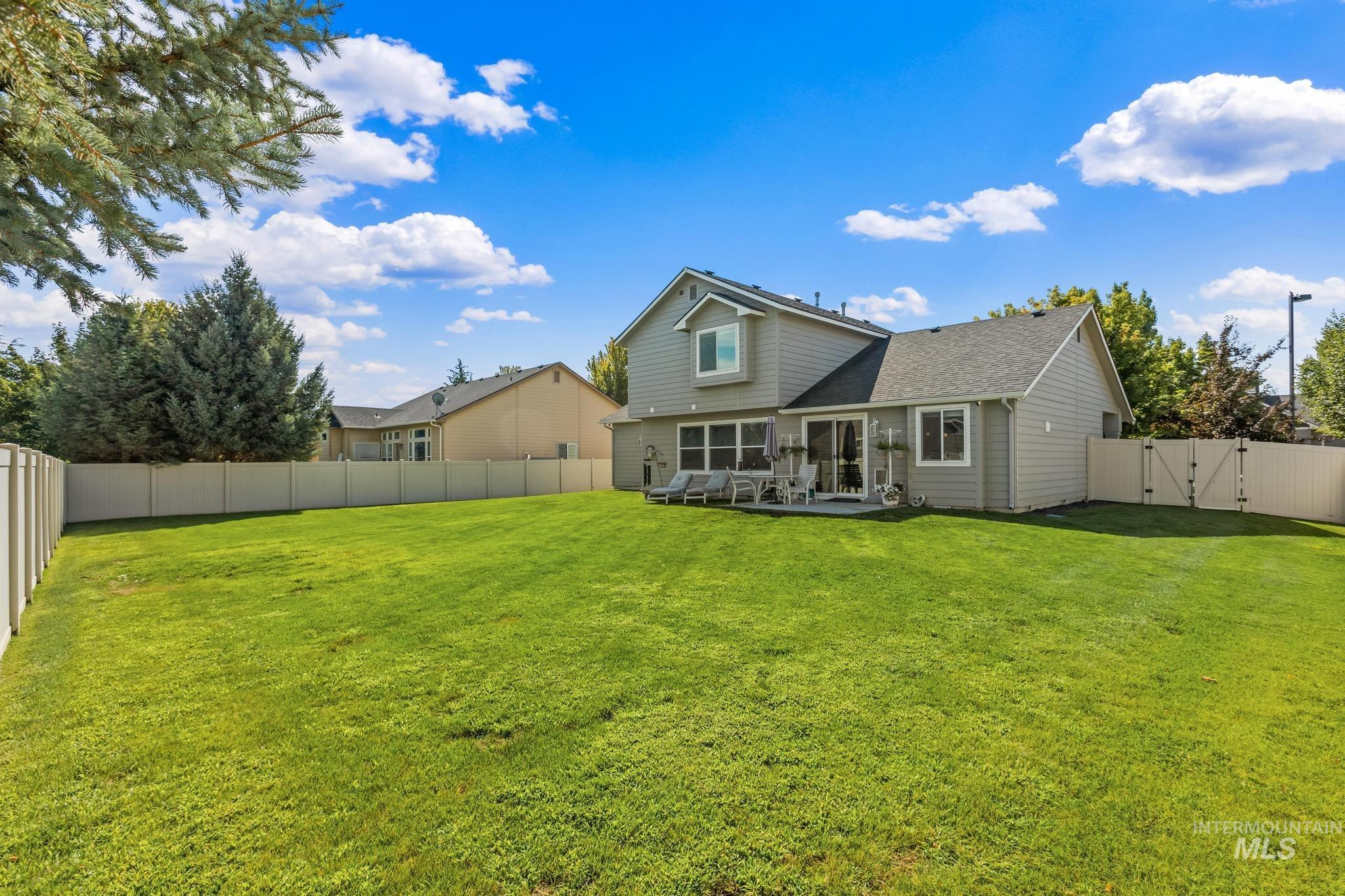 Back of property with a gate, a fenced backyard, and a shingled roof