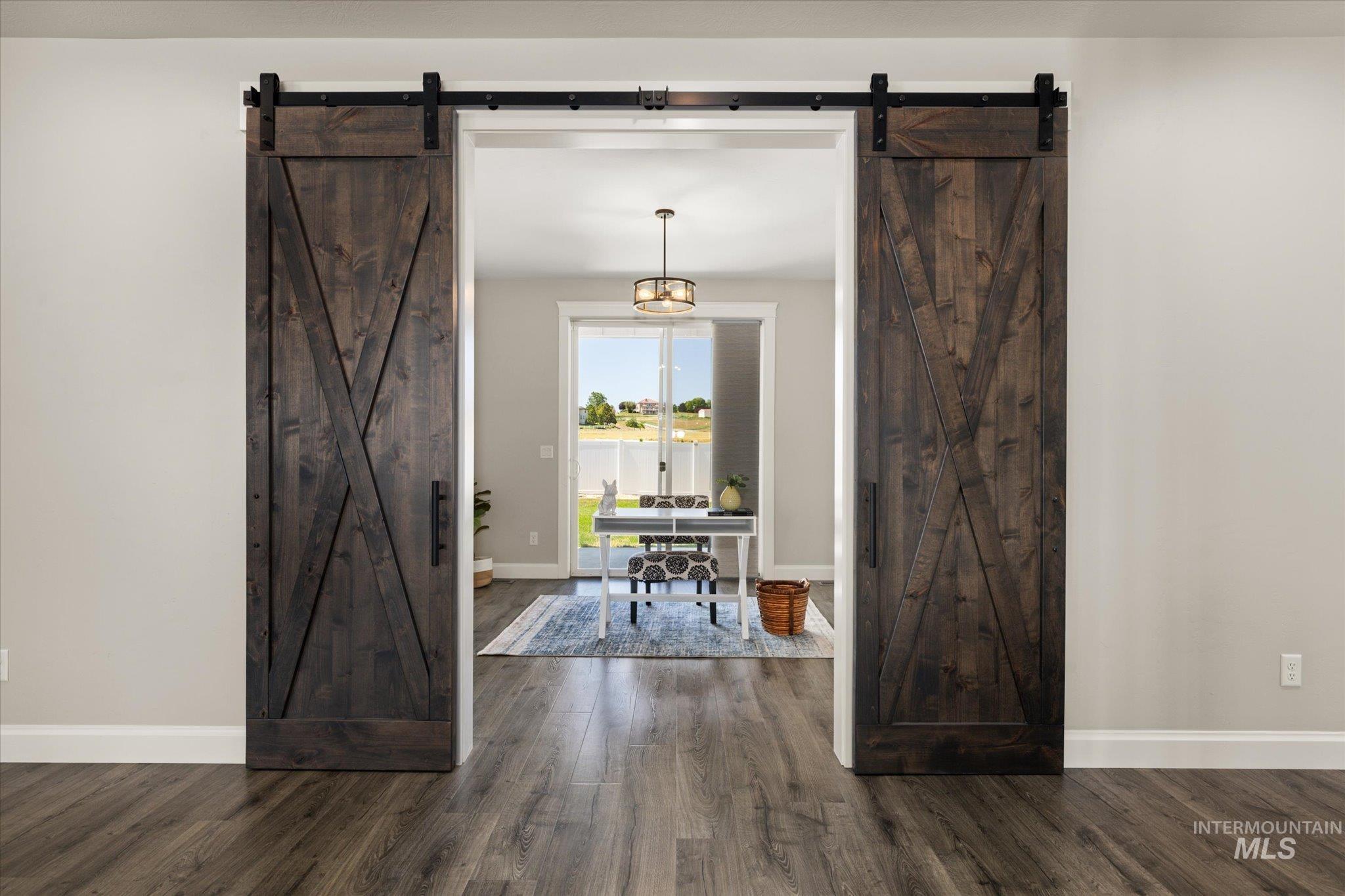 Foyer with a barn door and dark wood-style floors