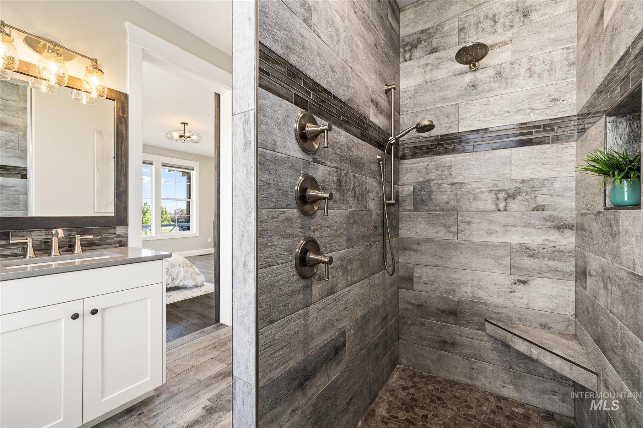 Bathroom with a tile shower, vanity, and wood finished floors