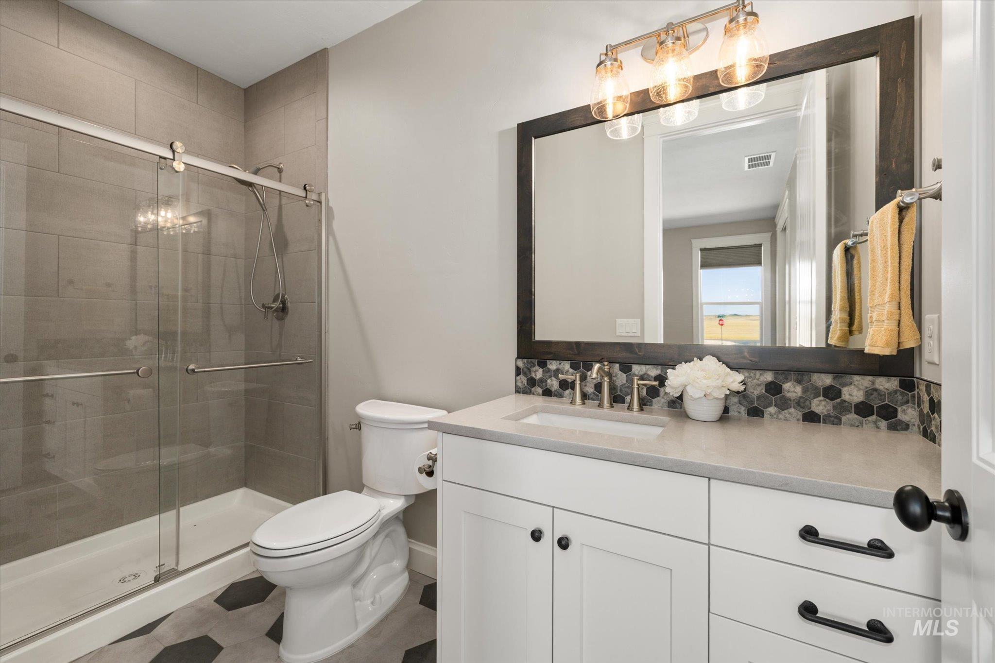 Bathroom with vanity, a stall shower, and decorative backsplash
