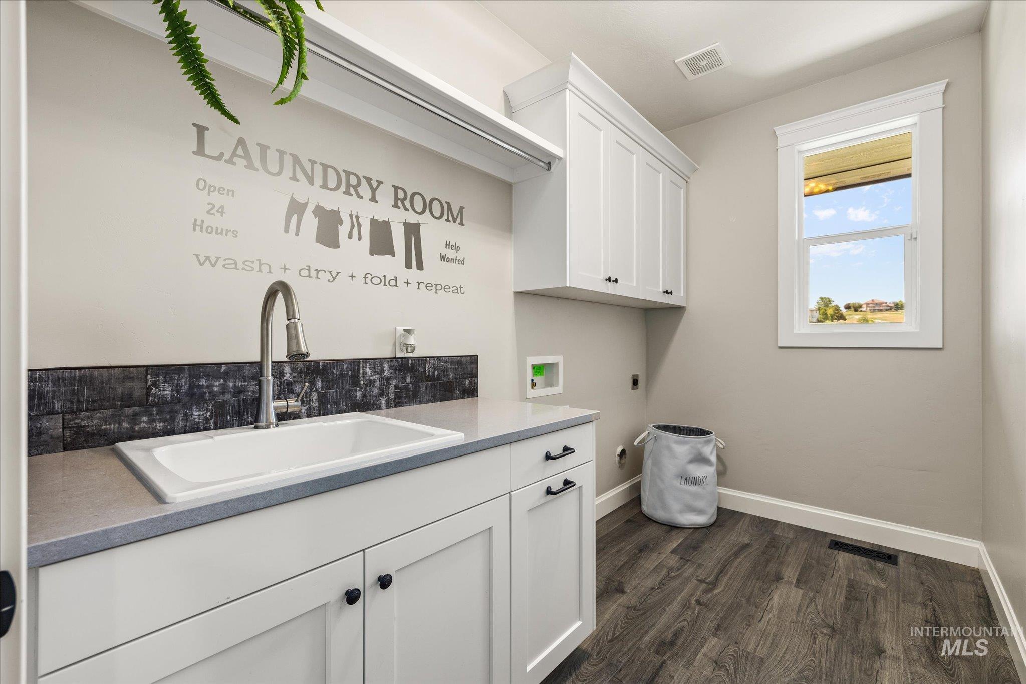 Laundry area with cabinet space, hookup for an electric dryer, dark wood-style flooring, and hookup for a washing machine