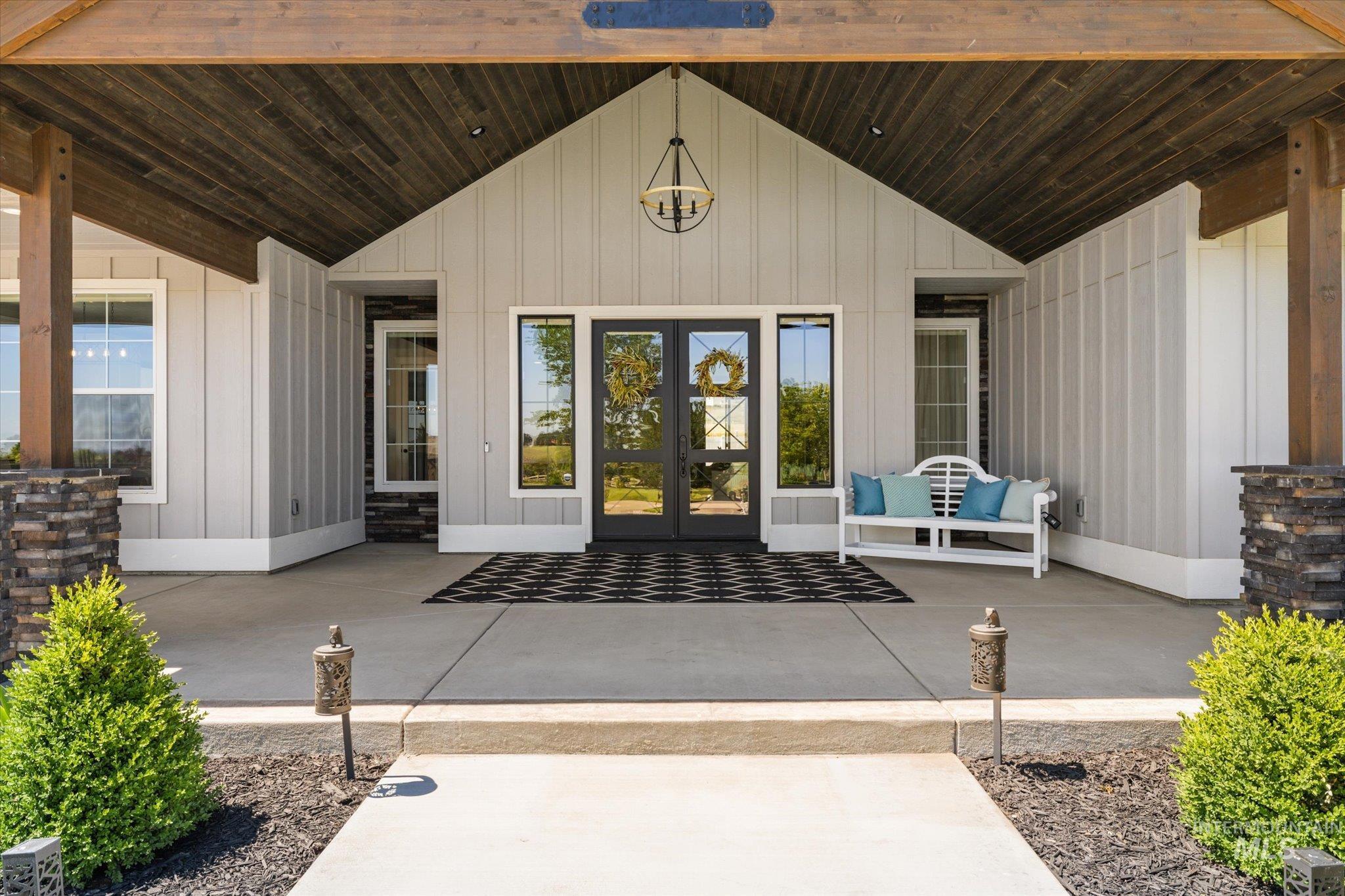 Doorway to property with french doors, board and batten siding, and a patio area