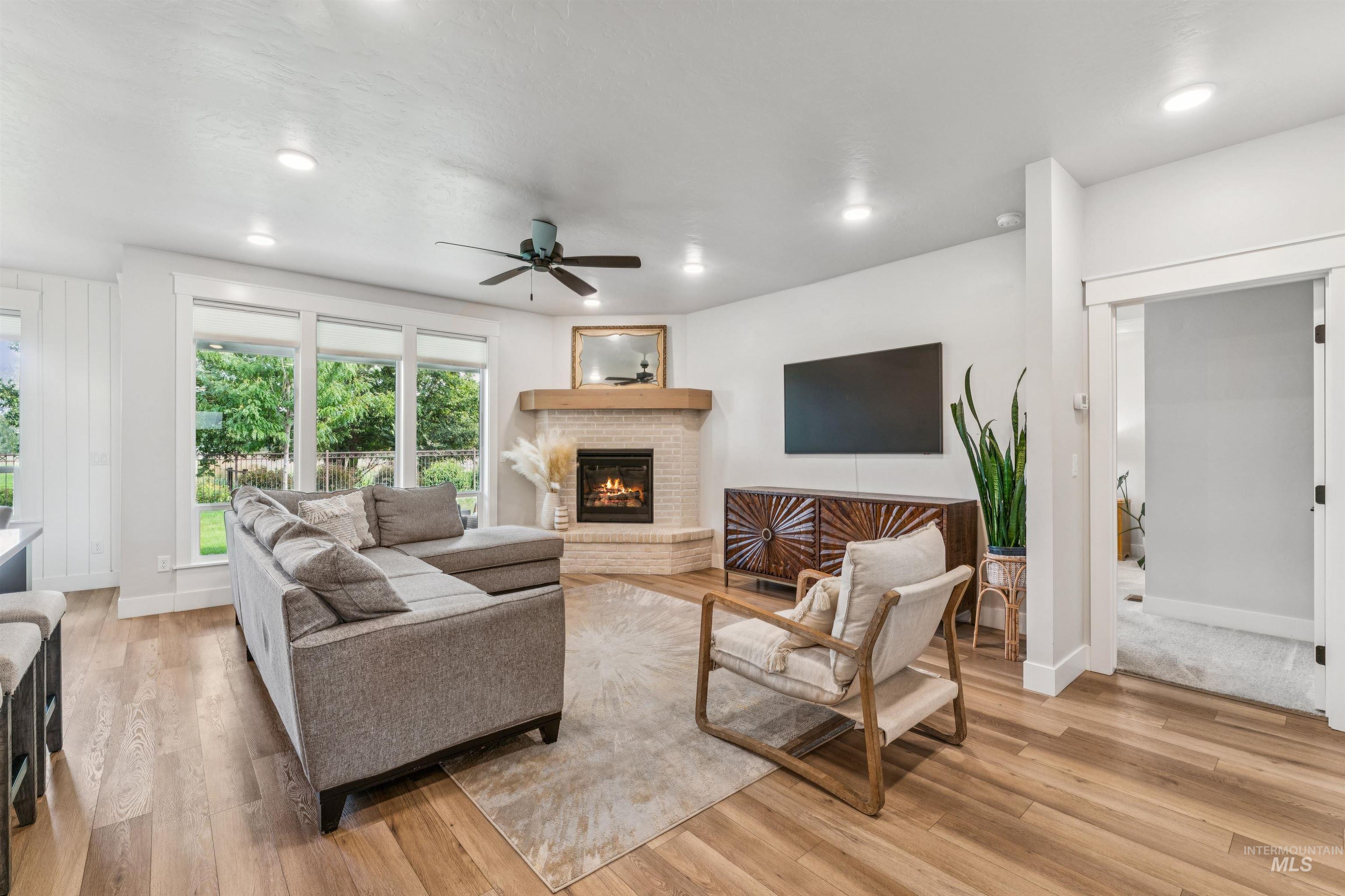 Living area with a fireplace, light wood-style floors, a ceiling fan, and recessed lighting